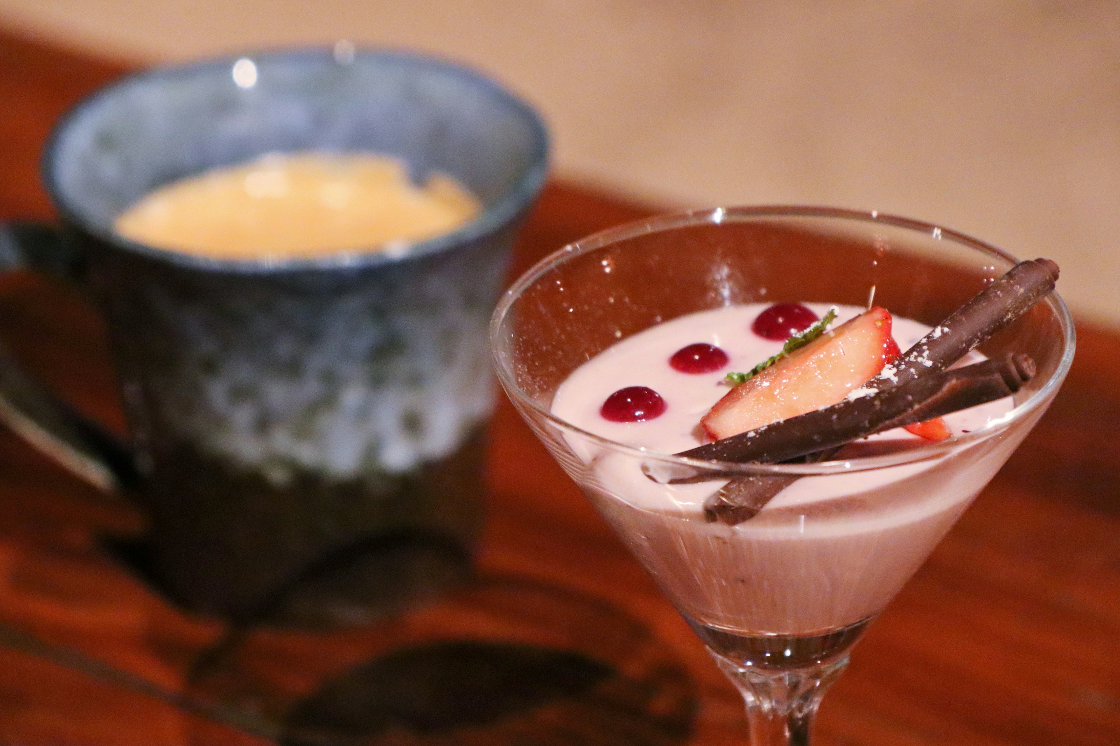 Cocktail glass with fruit and chocolate toppings alongside a blue ceramic cup