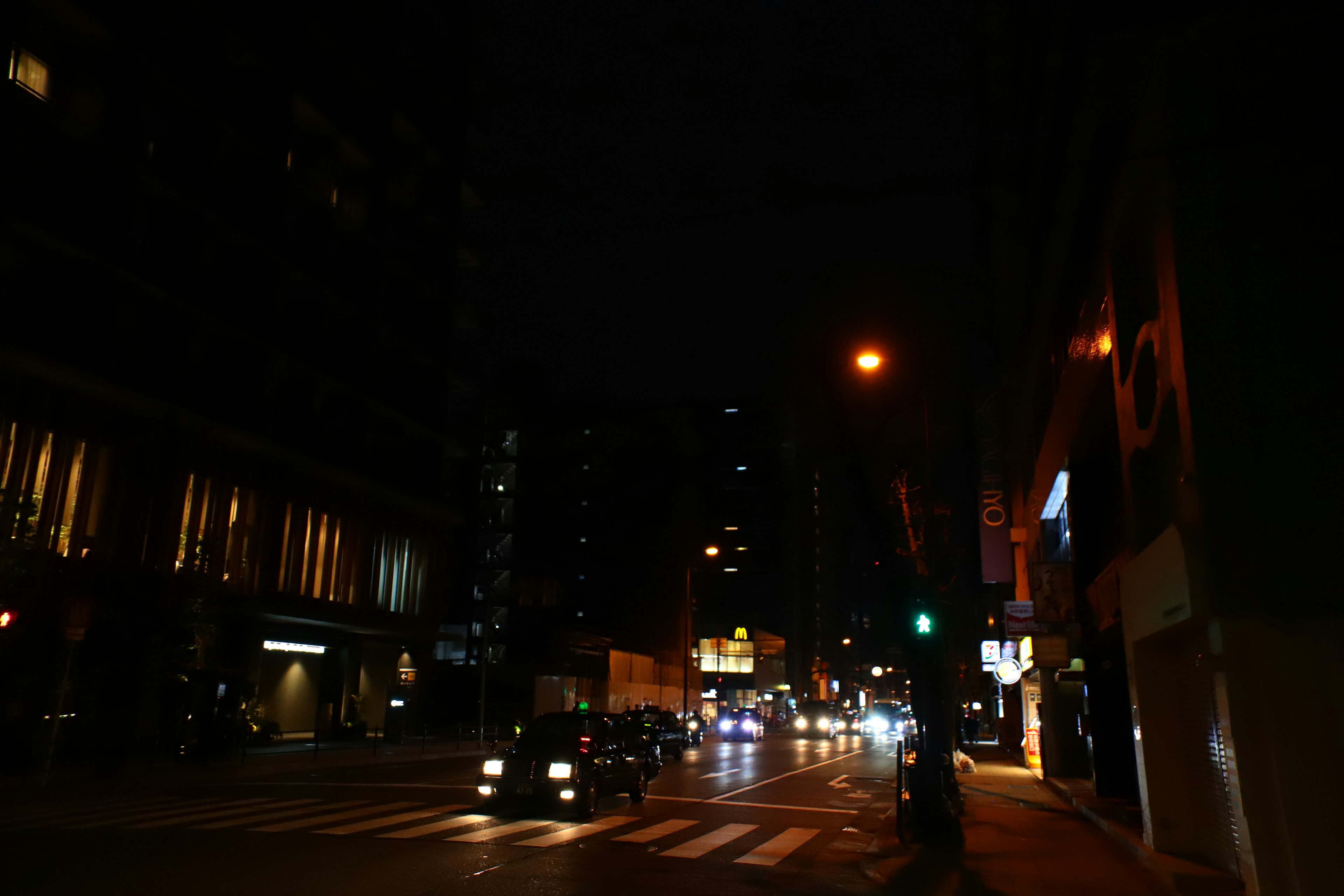 Night cityscape with cars at intersection, illuminated buildings, traffic light