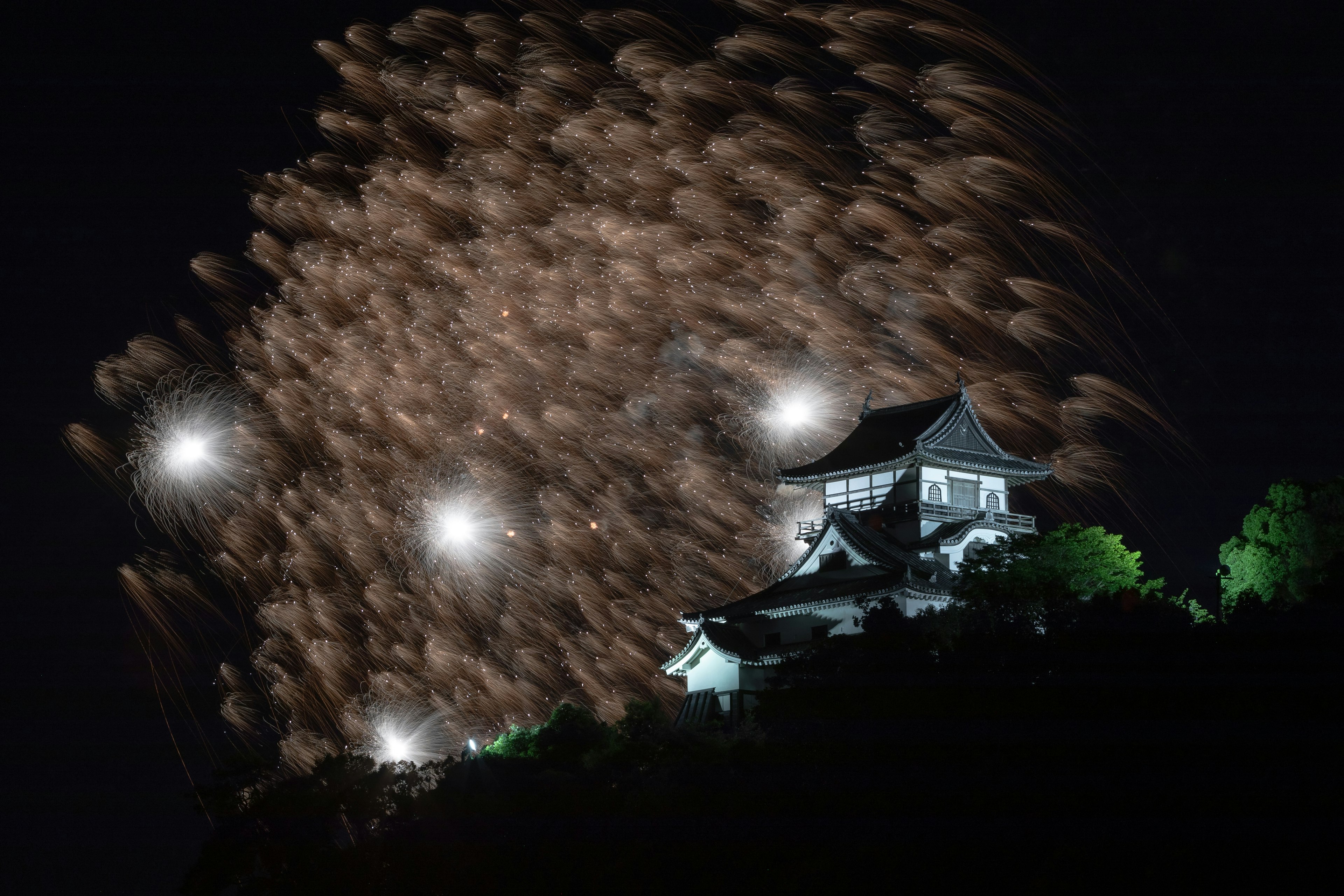 夜空中盛开的烟花与下方的传统日本城堡的美丽景观