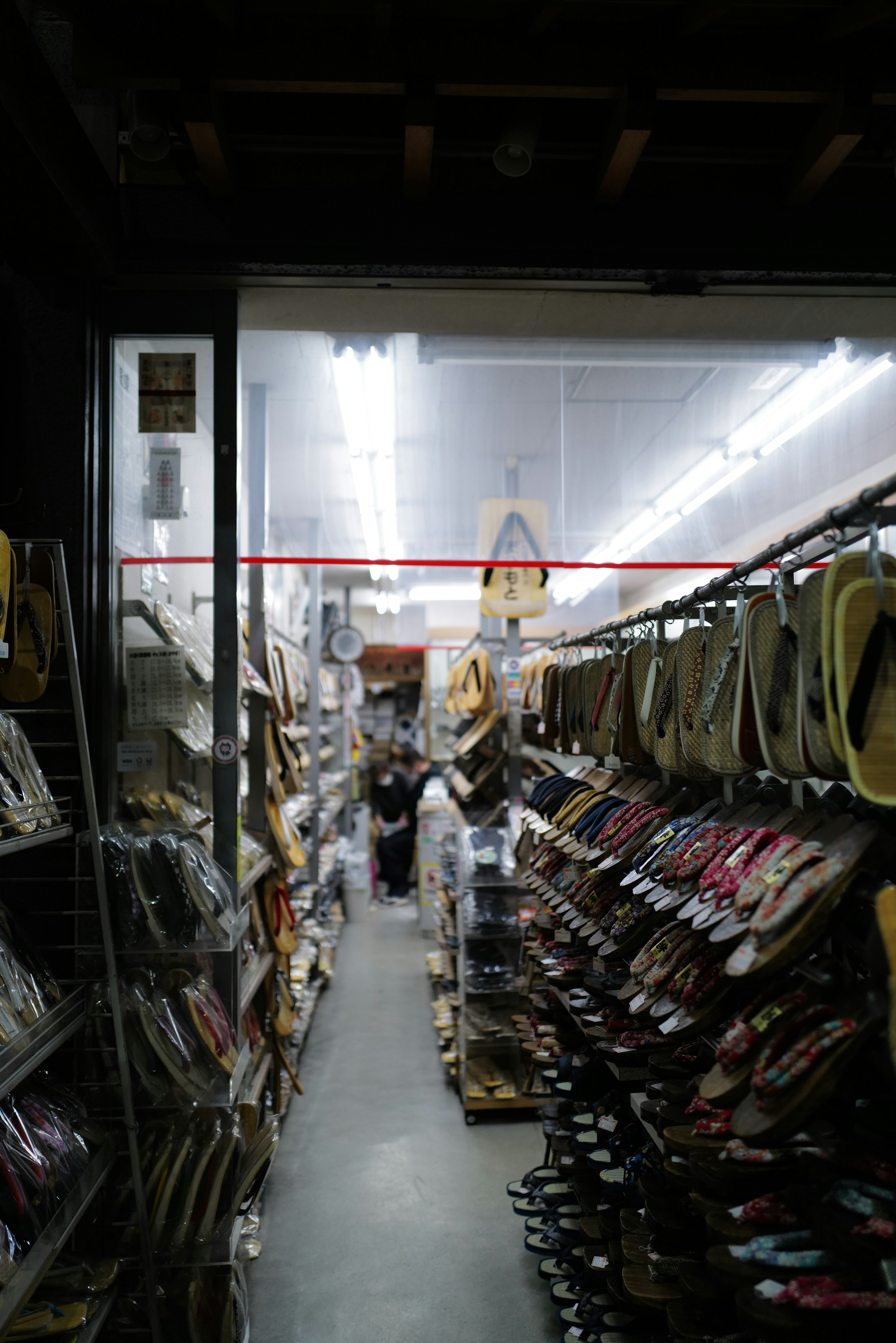 Narrow aisle in a store filled with various products under bright lighting