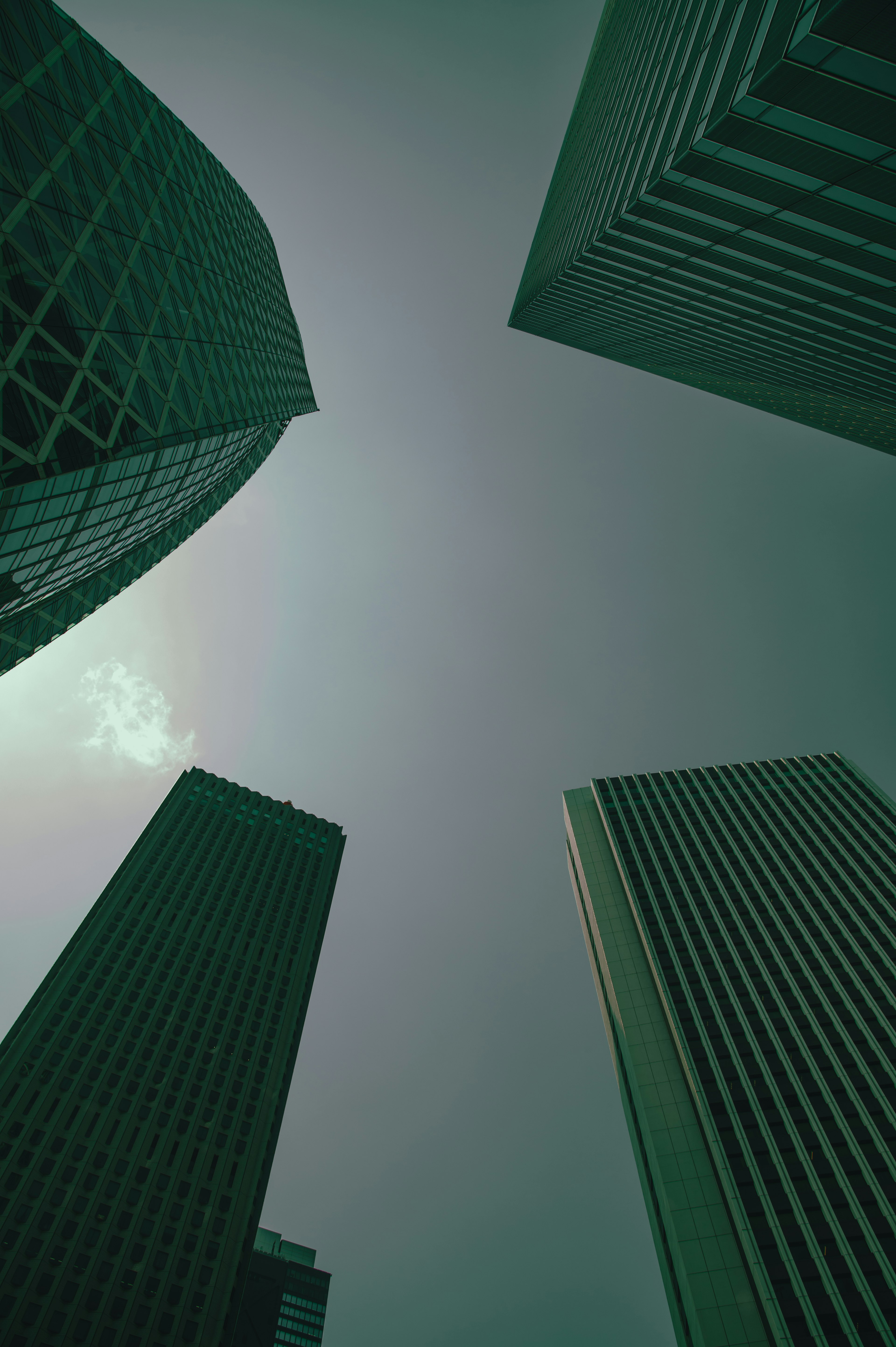 Photo looking up at skyscrapers with a greenish sky