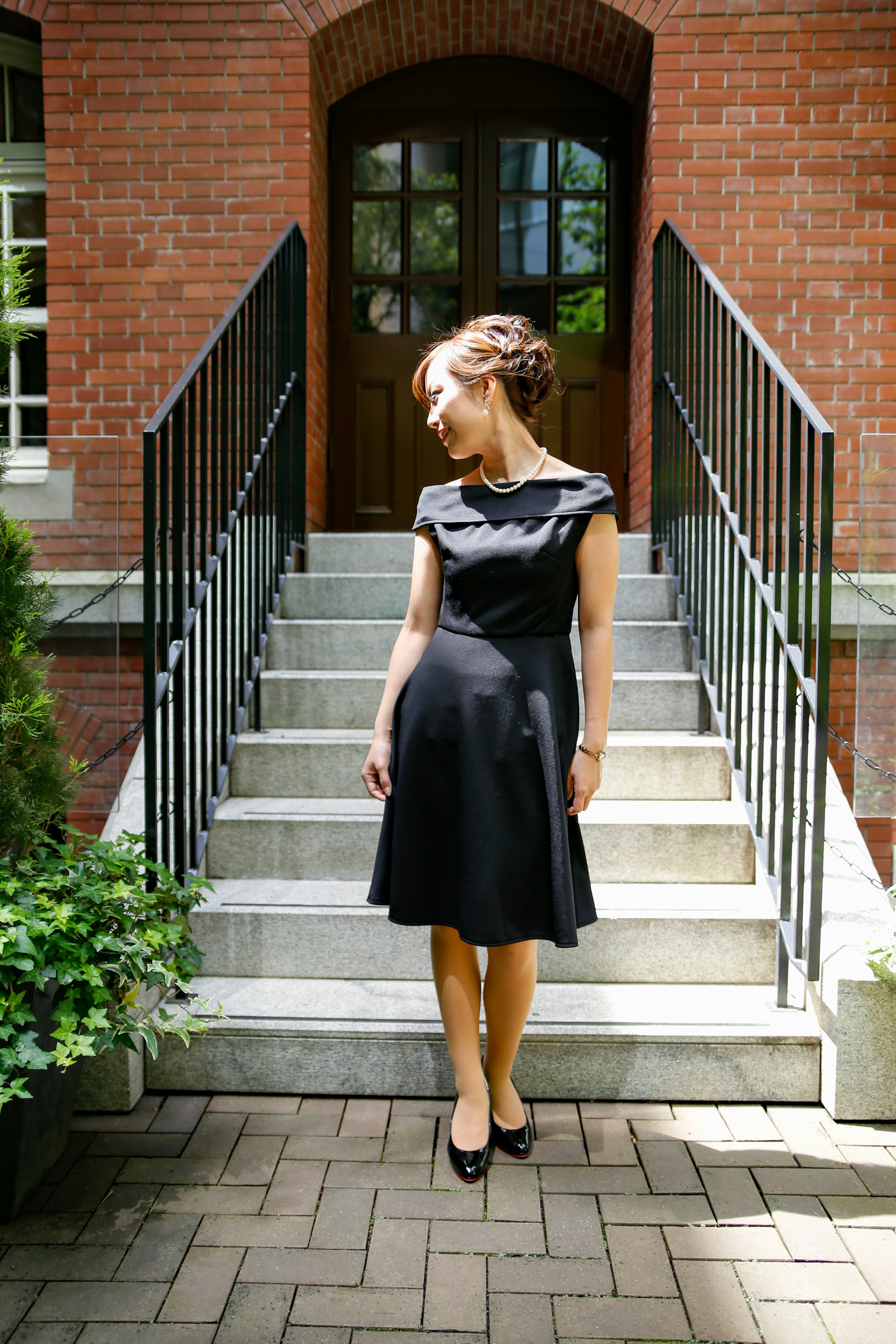 Eine Frau in einem schwarzen Kleid steht auf Treppen