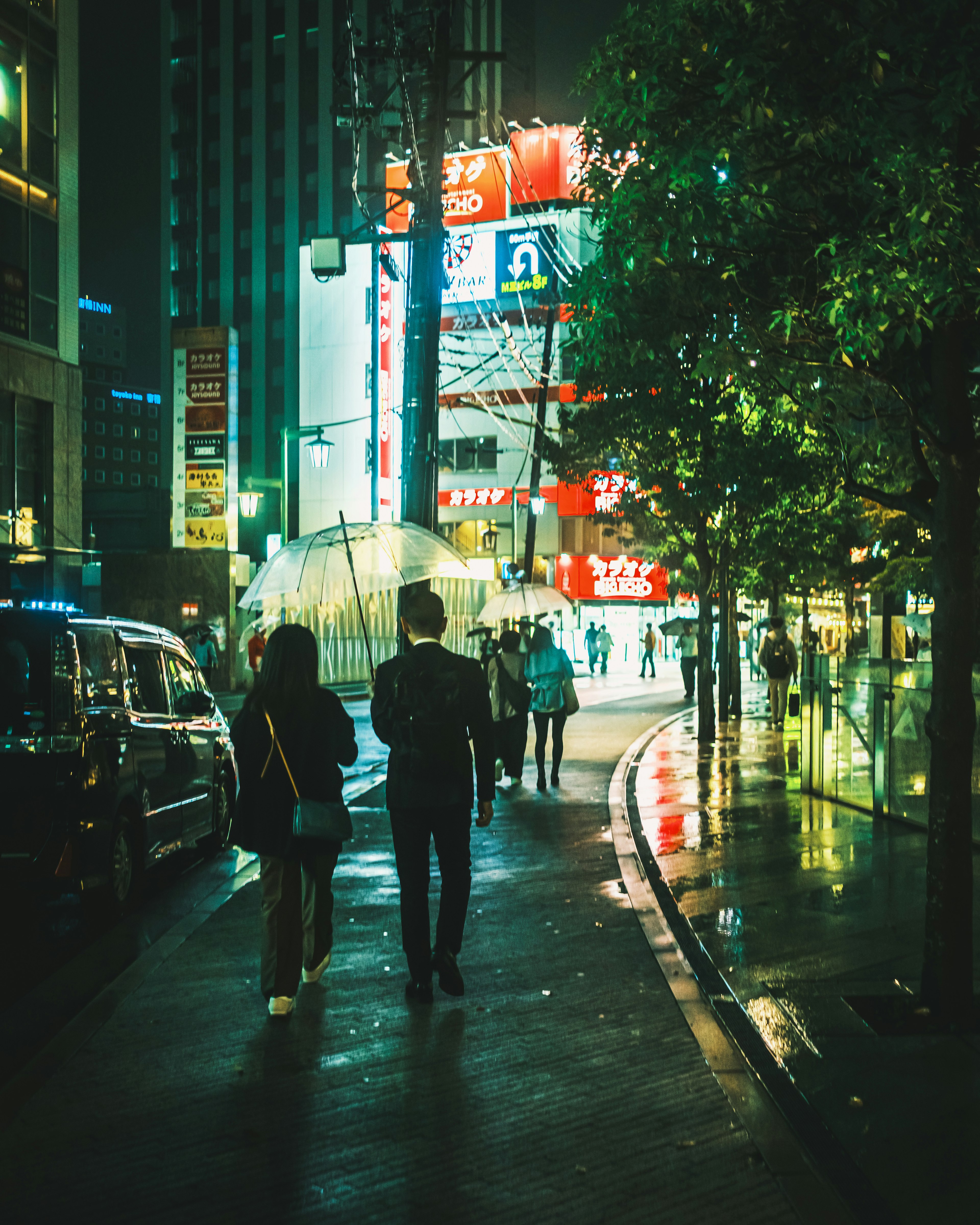 夜の街を歩くカップルと繁華街のネオン