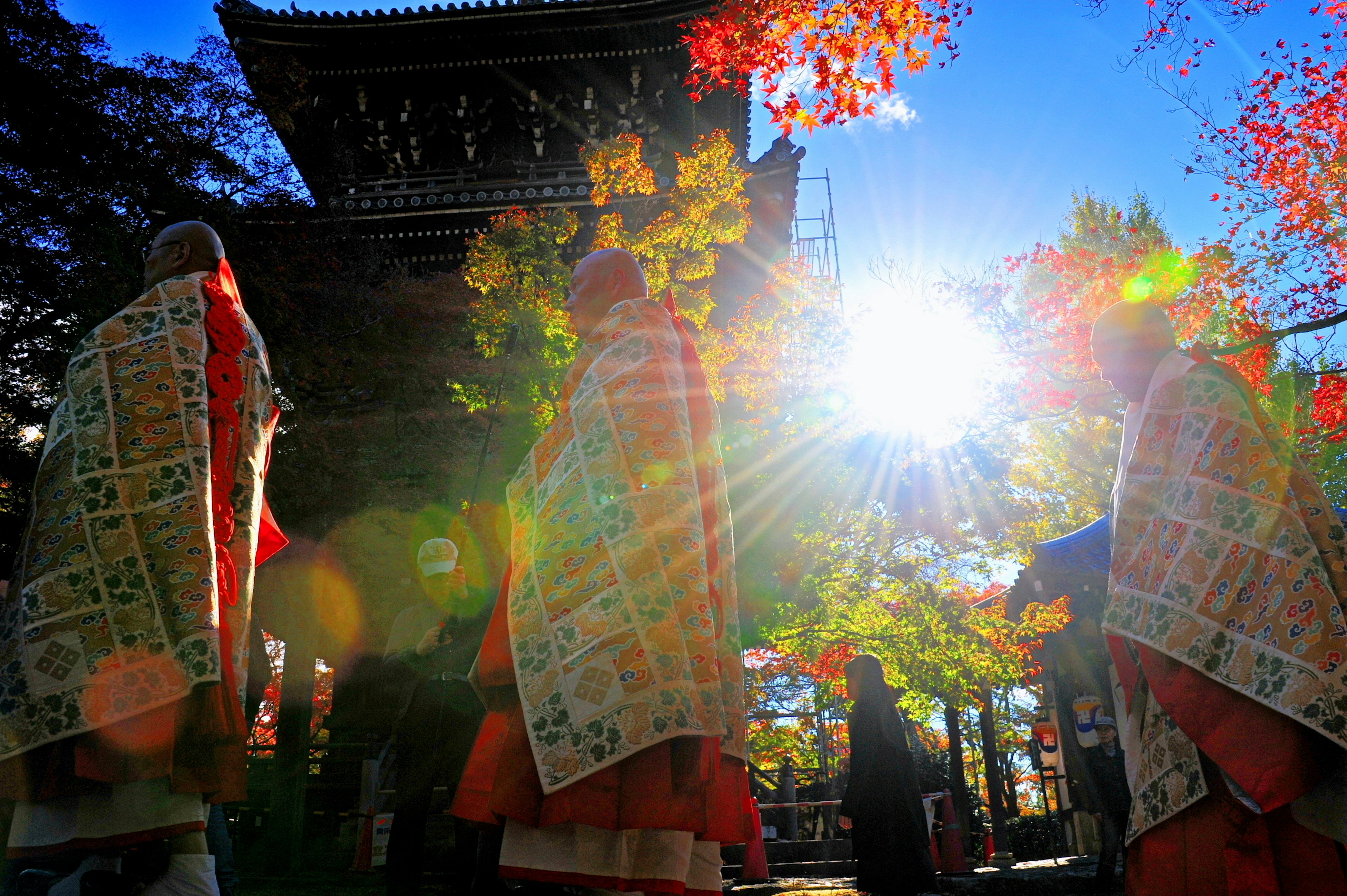 Des moines marchant parmi des feuilles d'automne avec un temple en arrière-plan