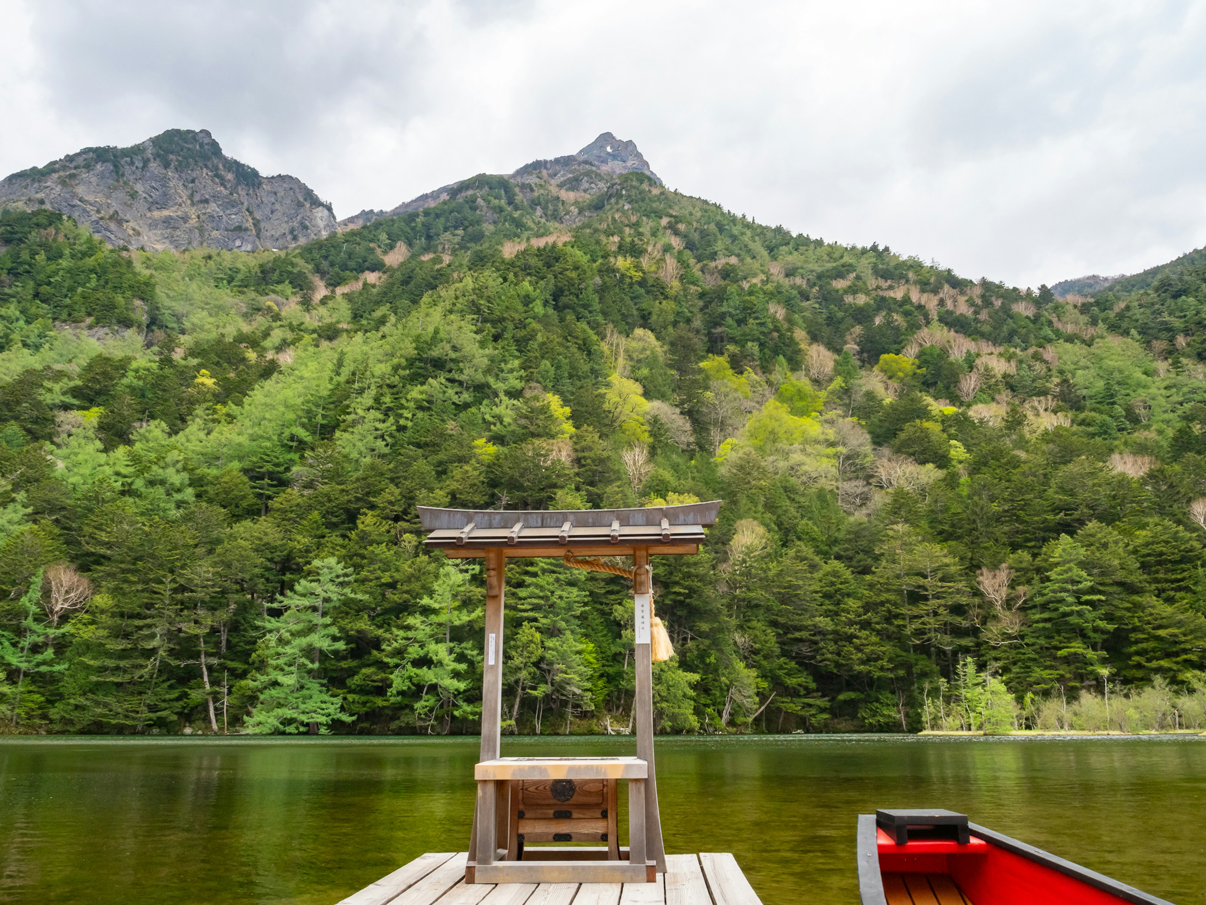 A tranquil lake scene with a small wooden dock surrounded by lush mountains