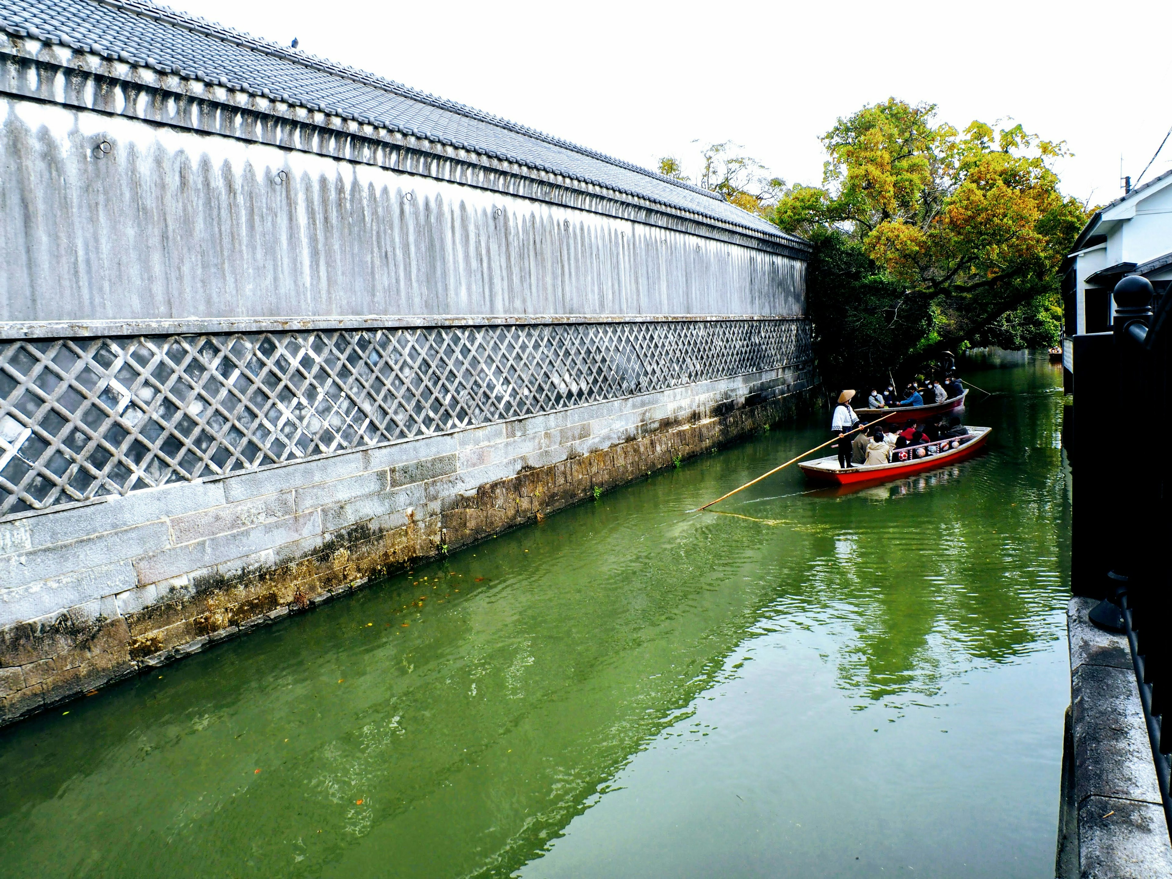 緑色の水路を進む小舟と古い壁の景色