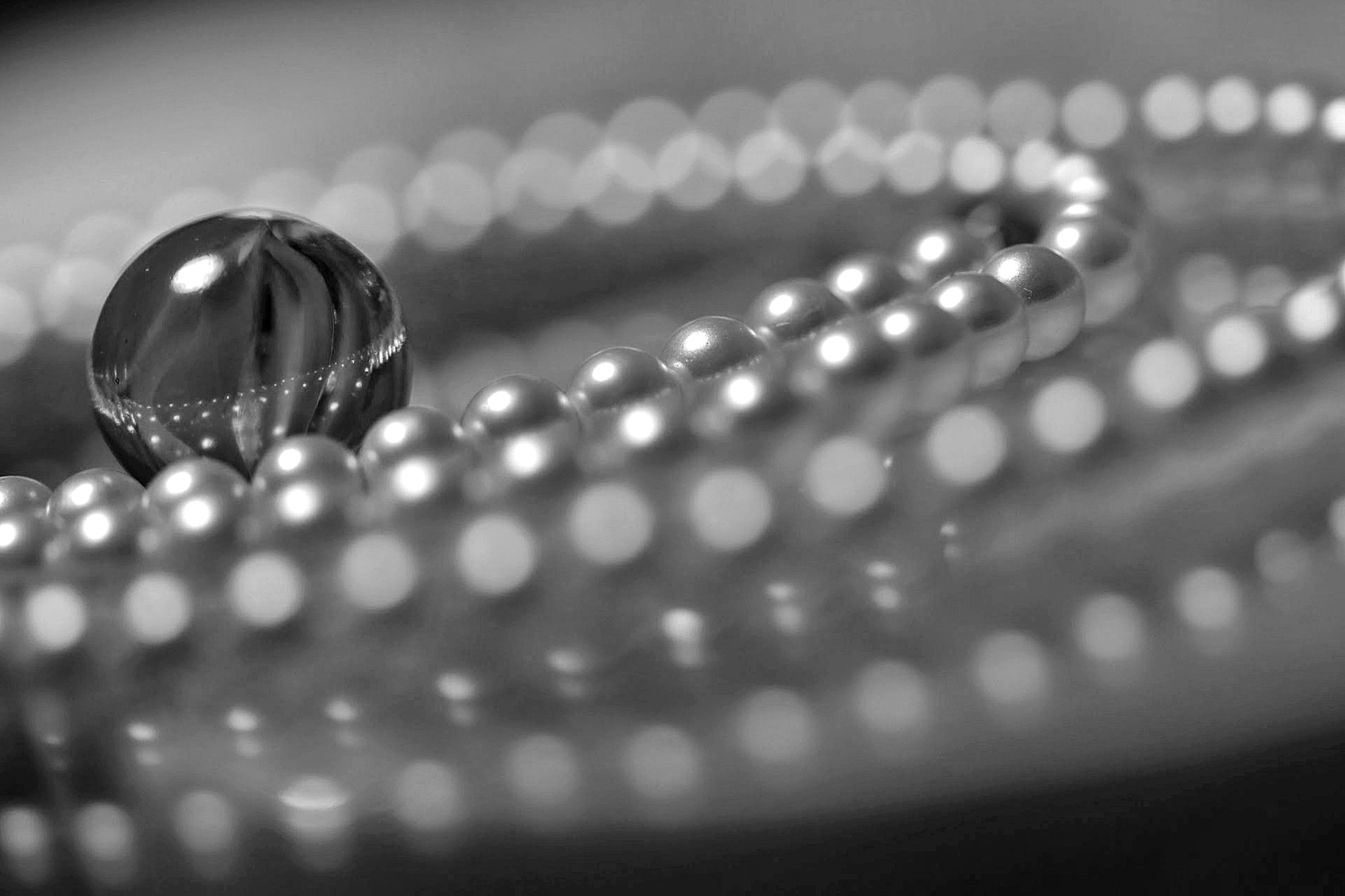 Gros plan sur un collier de perles et une goutte d'eau sur un fond noir et blanc