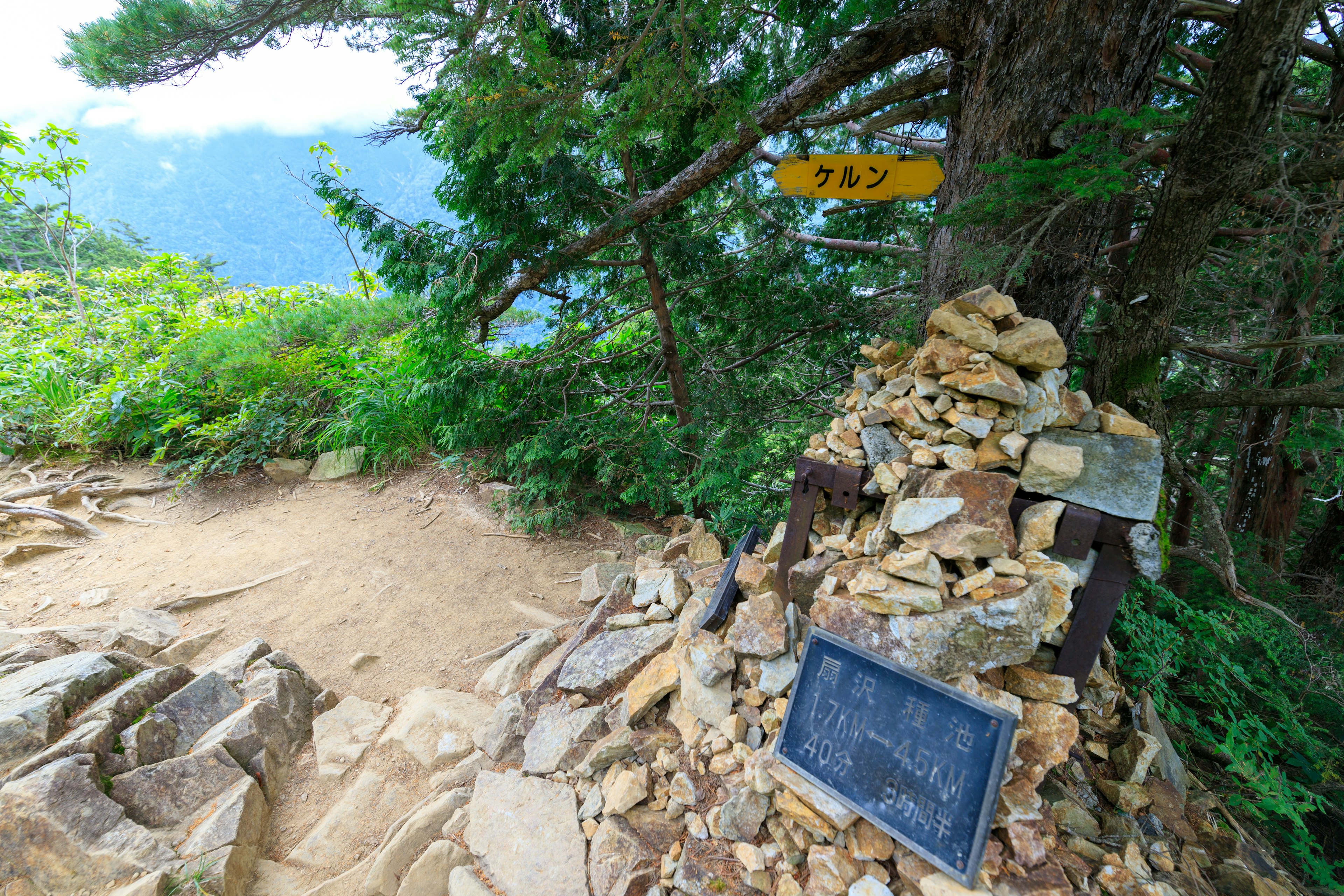 山道の標識と石の積み上げがある風景