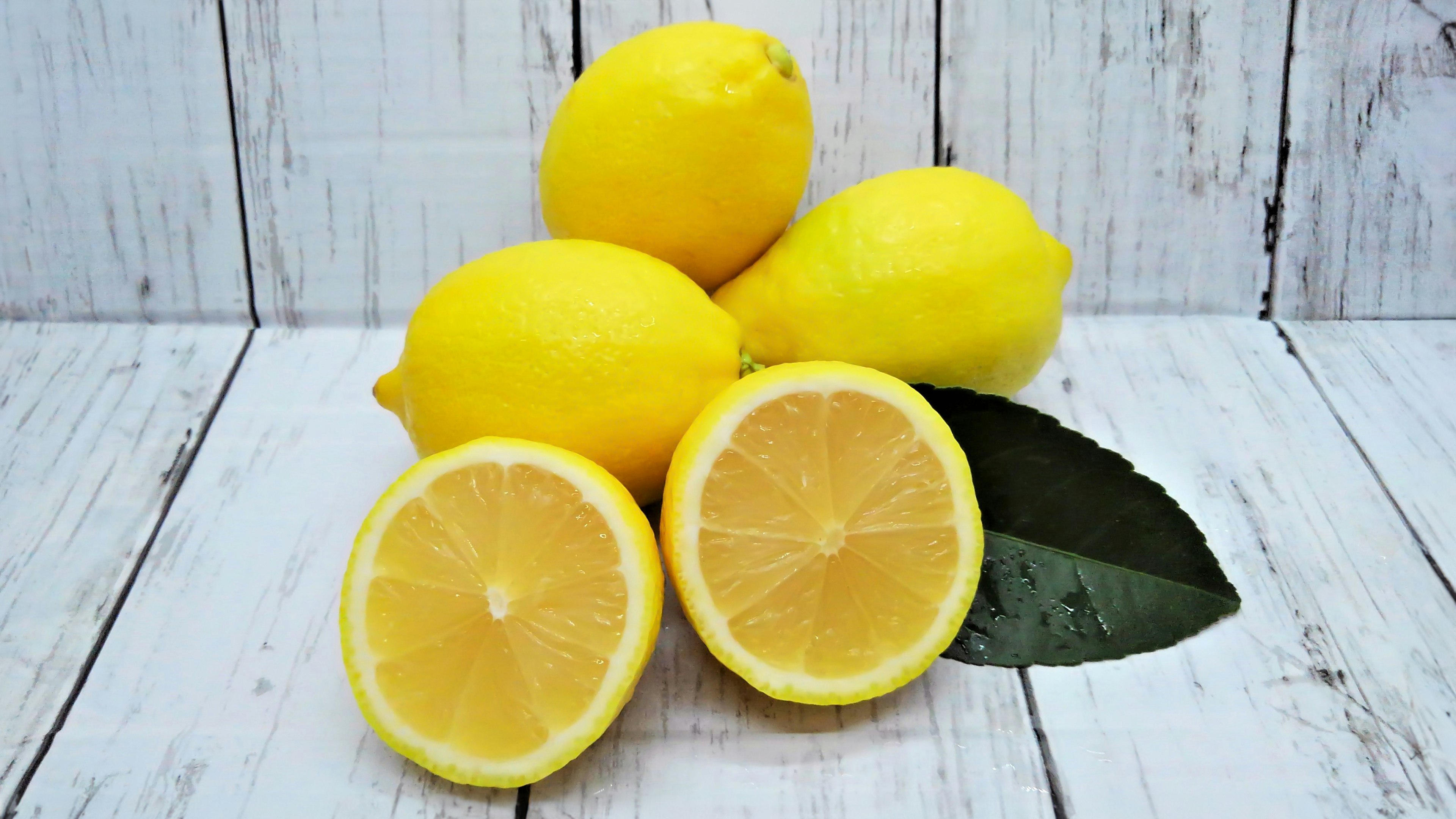 Limoni gialli brillanti con un limone affettato su una foglia