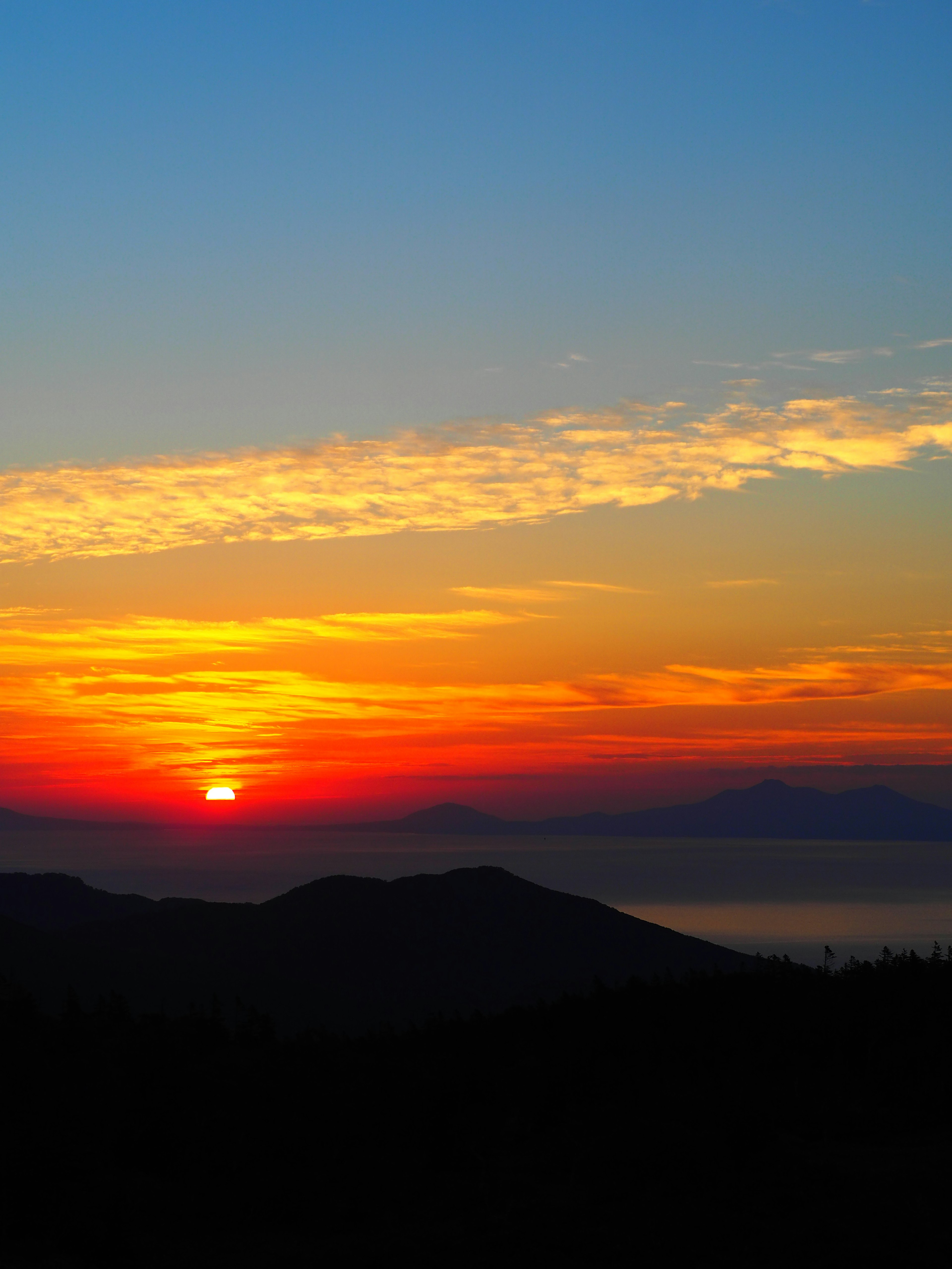 Wunderschöner Sonnenuntergang mit lebhaft orange-blauem Himmel über dem Meer