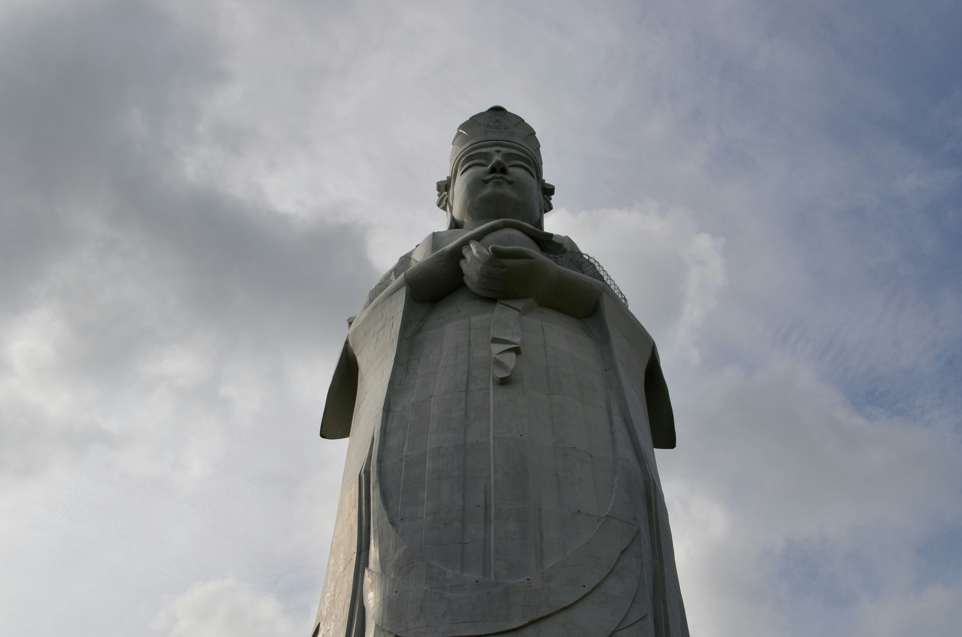 Grande statue blanche vue d'en bas avec les mains jointes devant