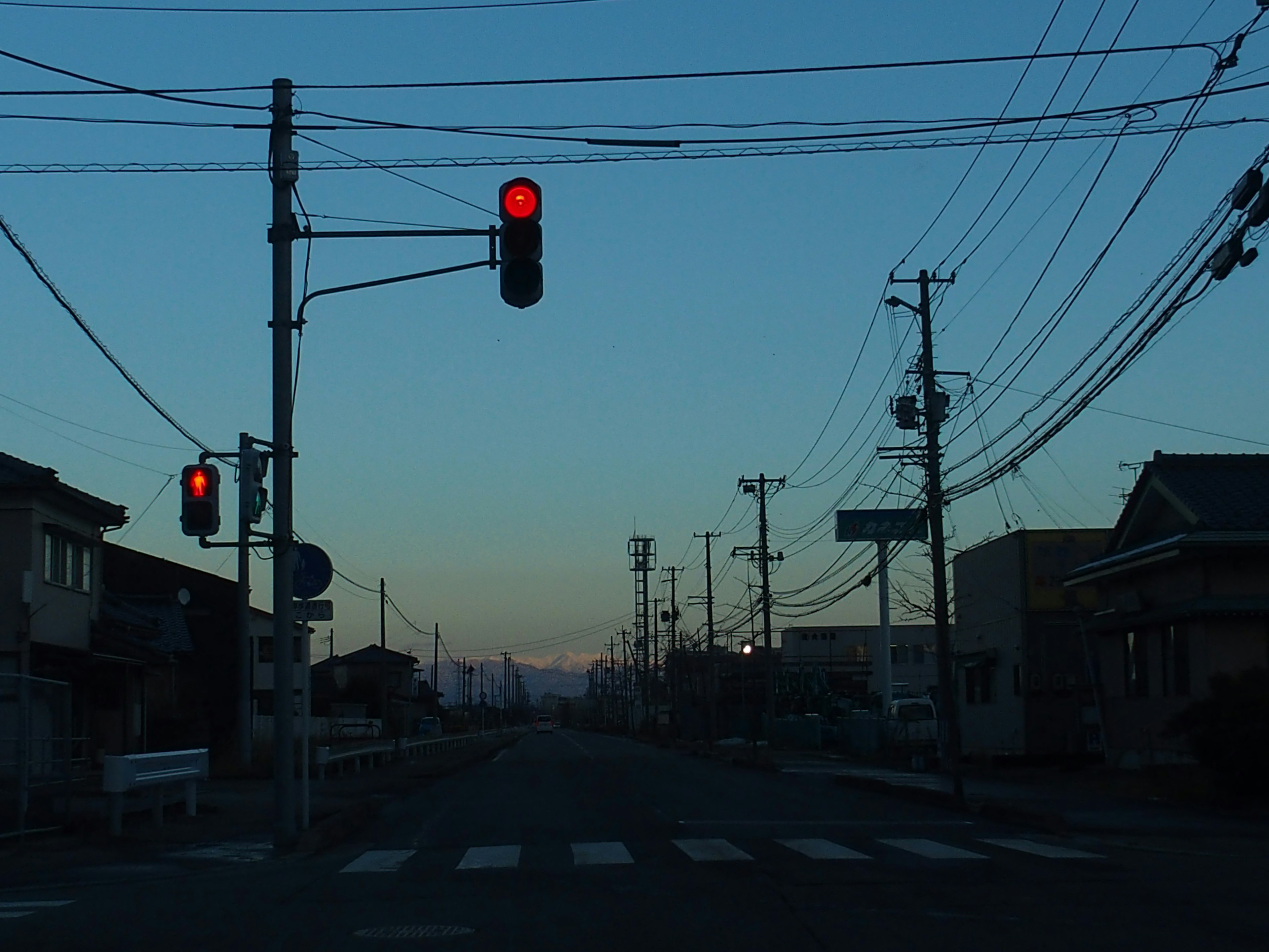 夕暮れ時の信号機と静かな街道の風景