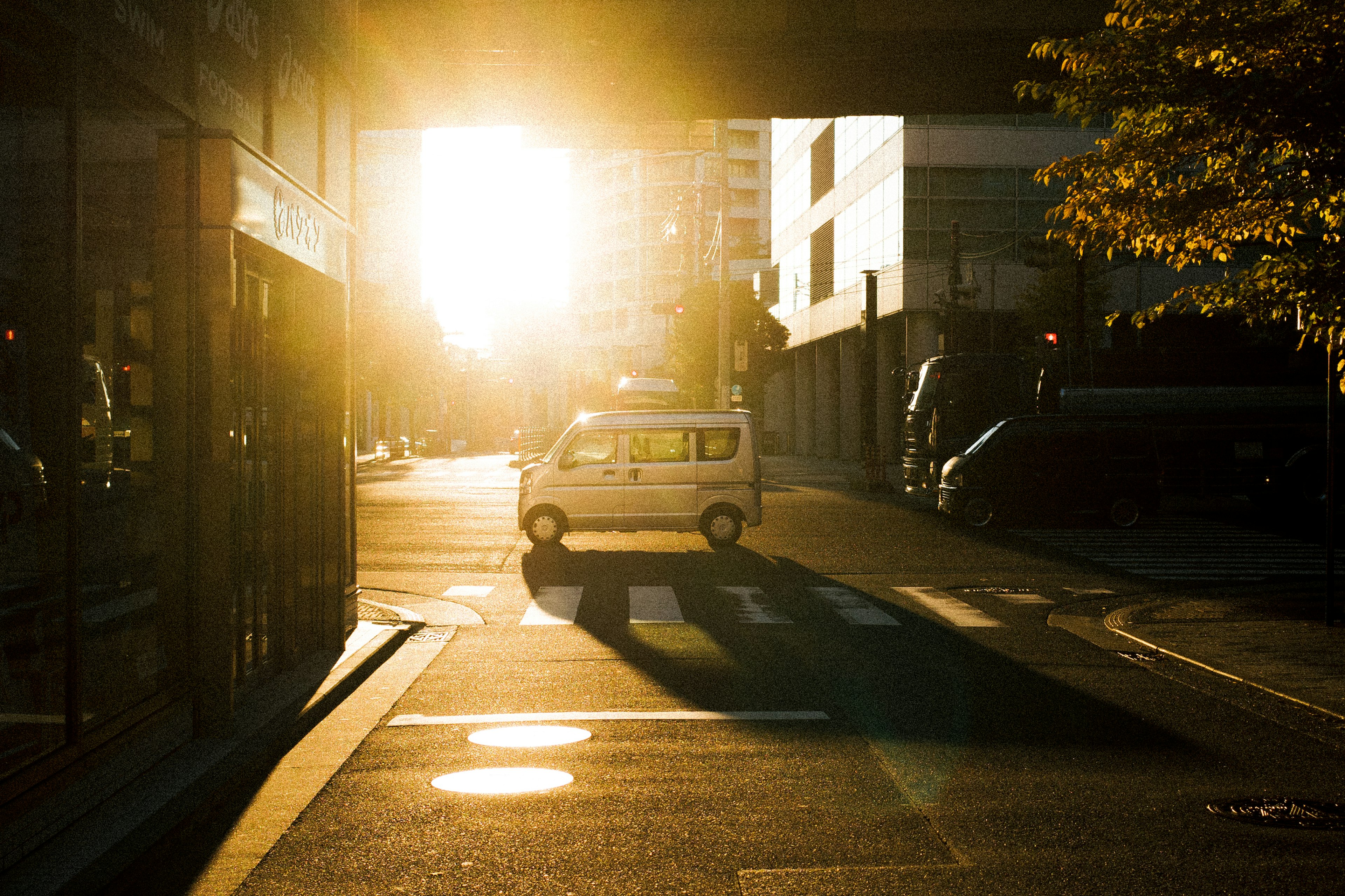 Silhouette d'une voiture circulant à un coin de rue éclairé par le coucher de soleil