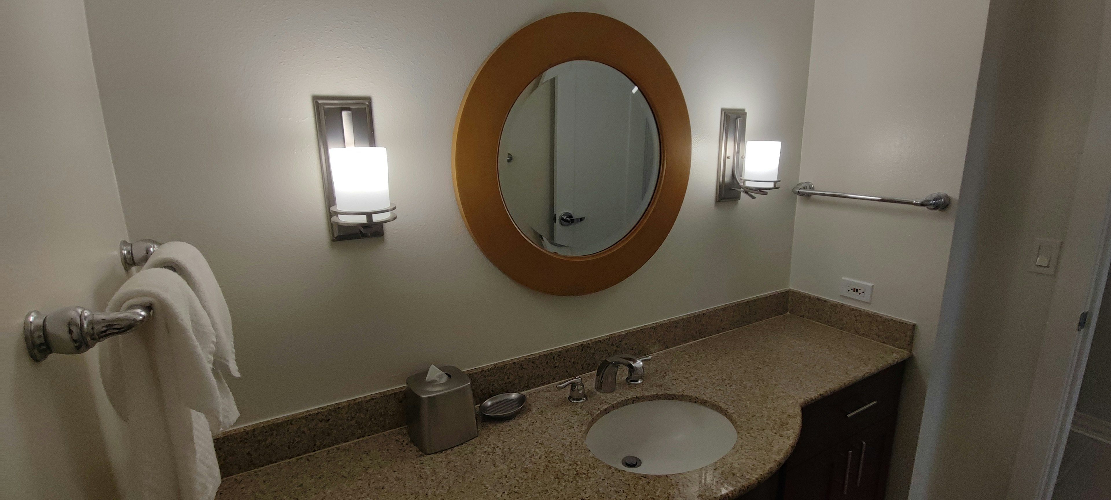 Interior of a clean bathroom with a sink Bright lighting and a round mirror are featured