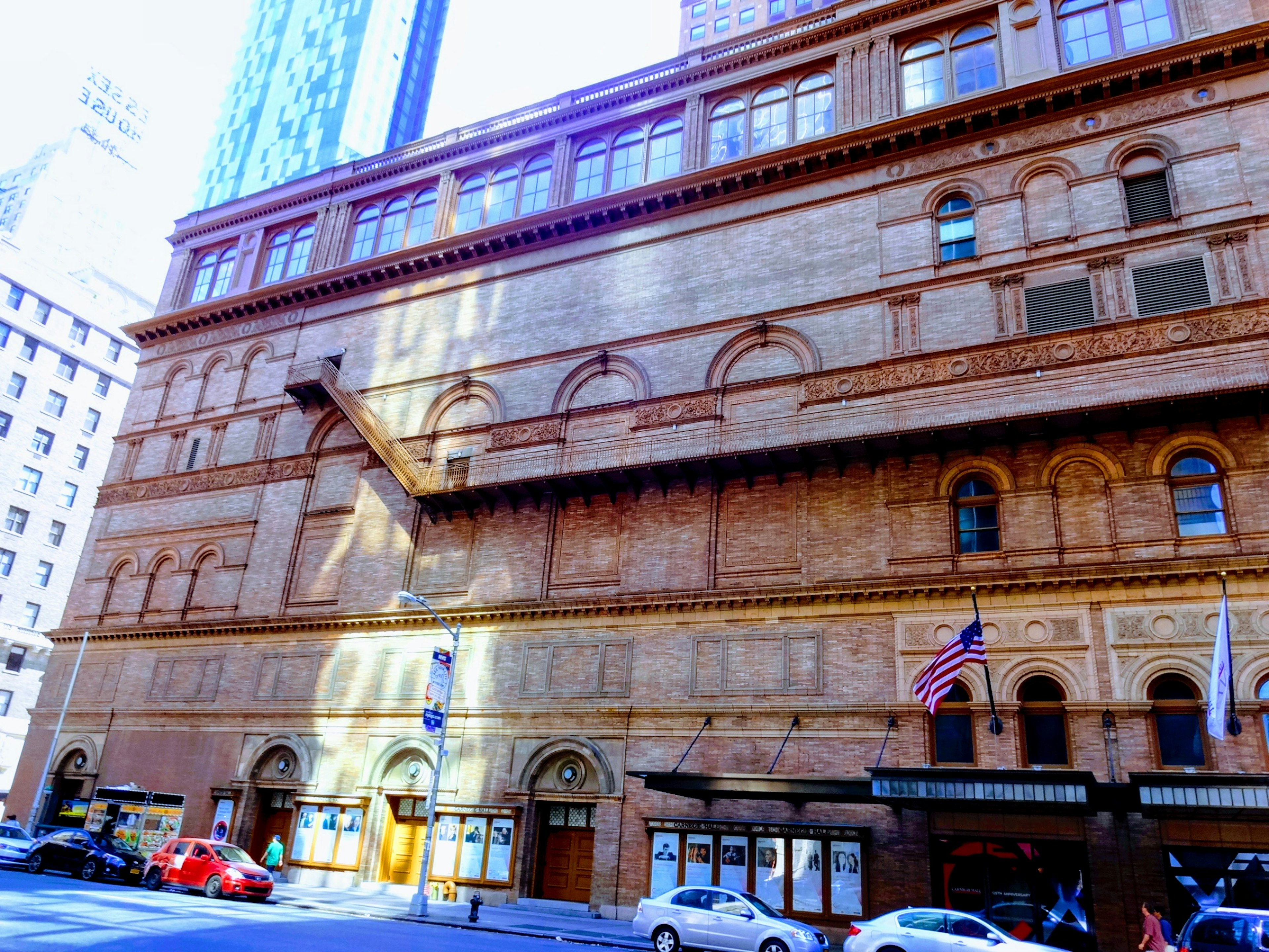 Vista esterna del Carnegie Hall con muri in mattoni finestre ad arco e ombre di luce