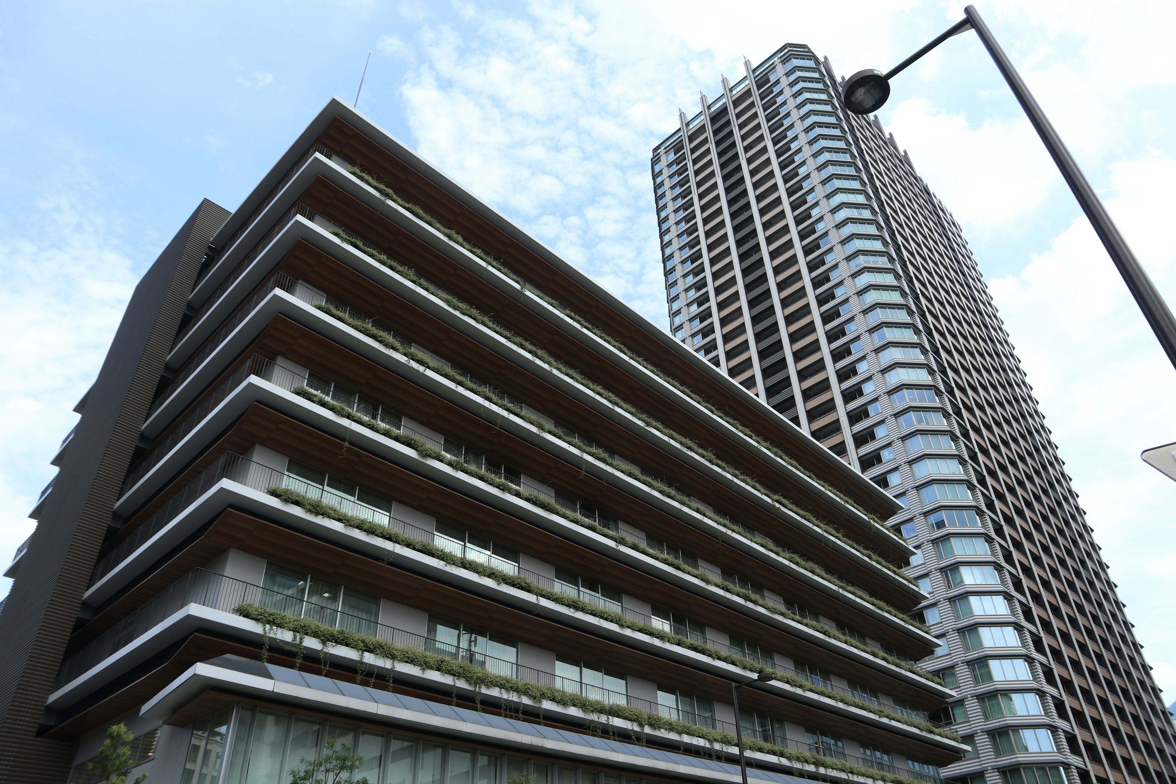 Foto che mostra un edificio moderno con balconi e un grattacielo alto