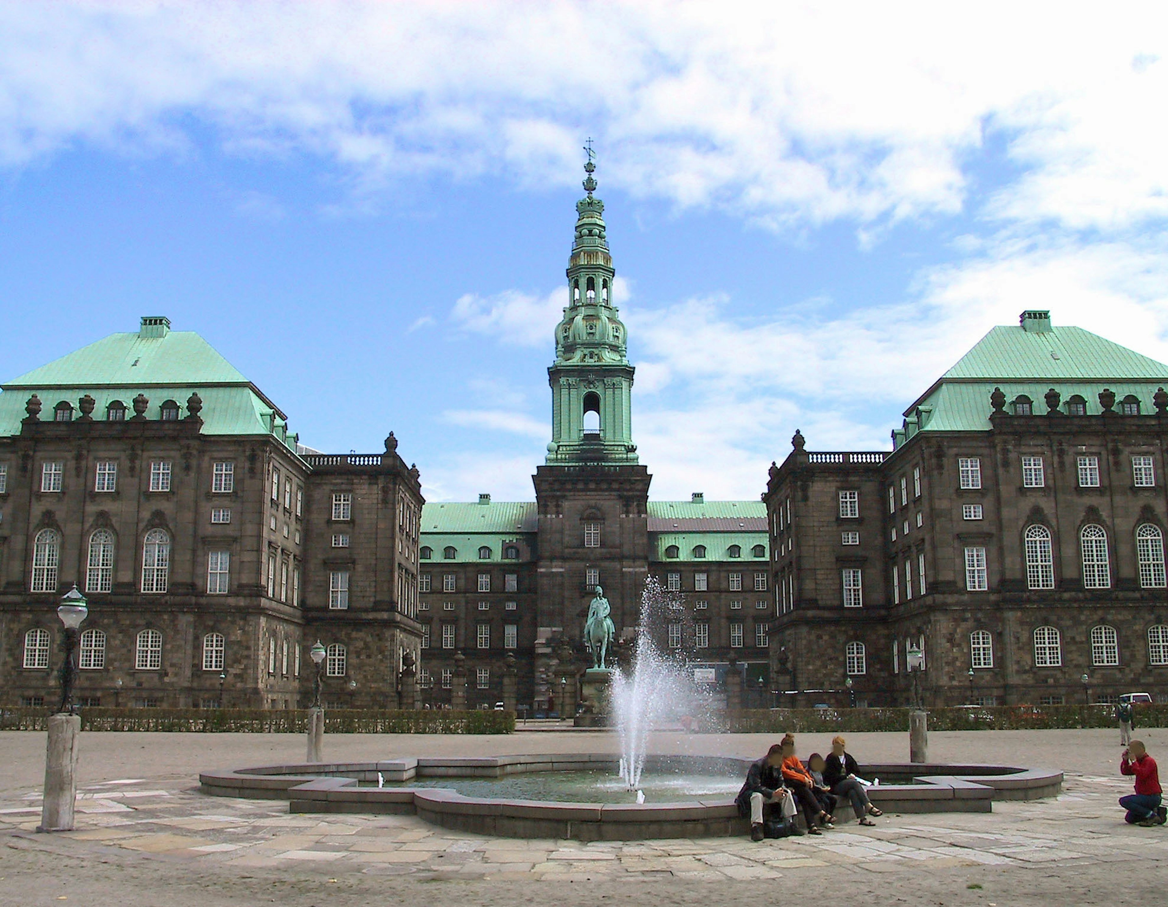 Vista exterior del Palacio de Christiansborg en Copenhague con techos verdes y una fuente