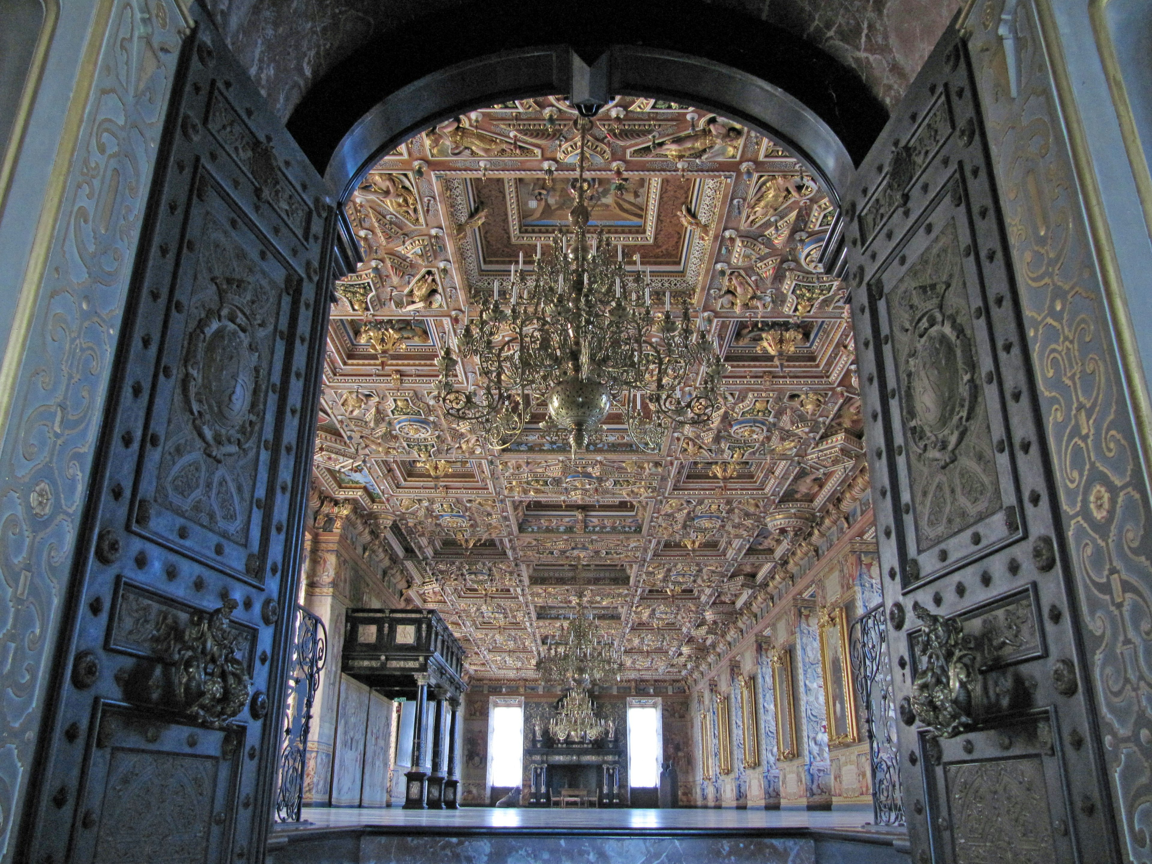 Large doors leading to a room with an ornate ceiling and chandelier