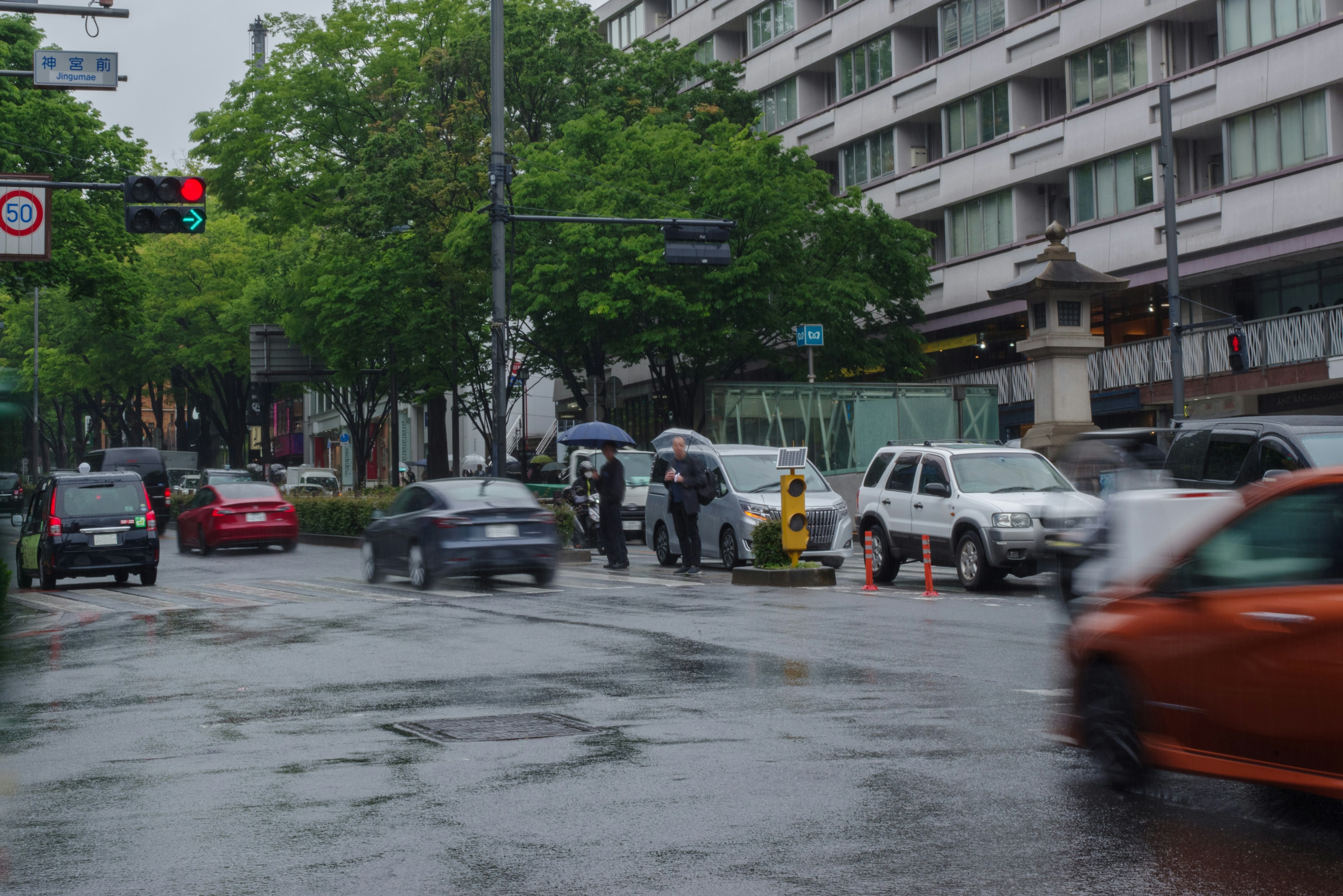 Intersección concurrida con peatones y vehículos bajo la lluvia