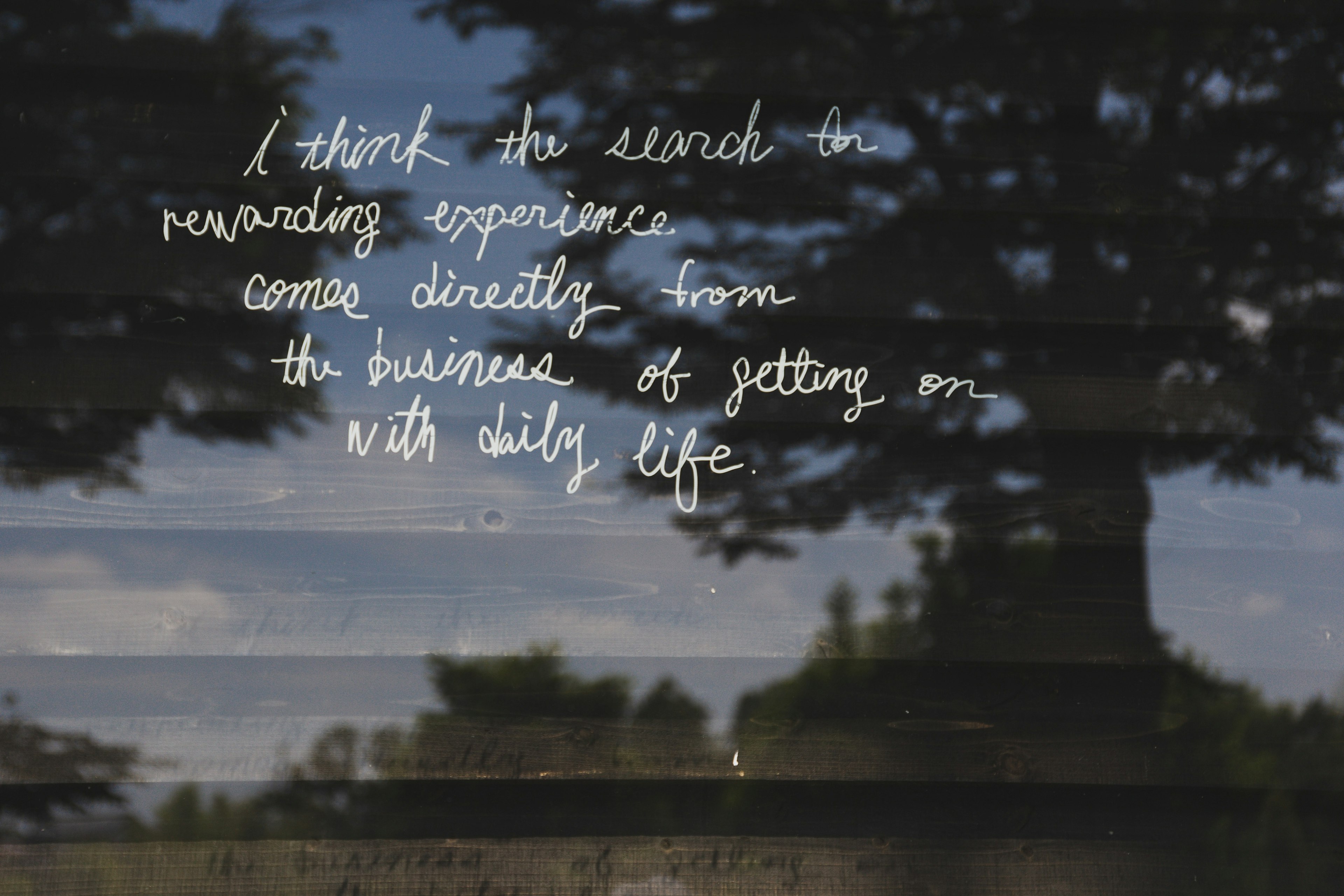 Una ventana reflectante que muestra un paisaje con texto escrito a mano