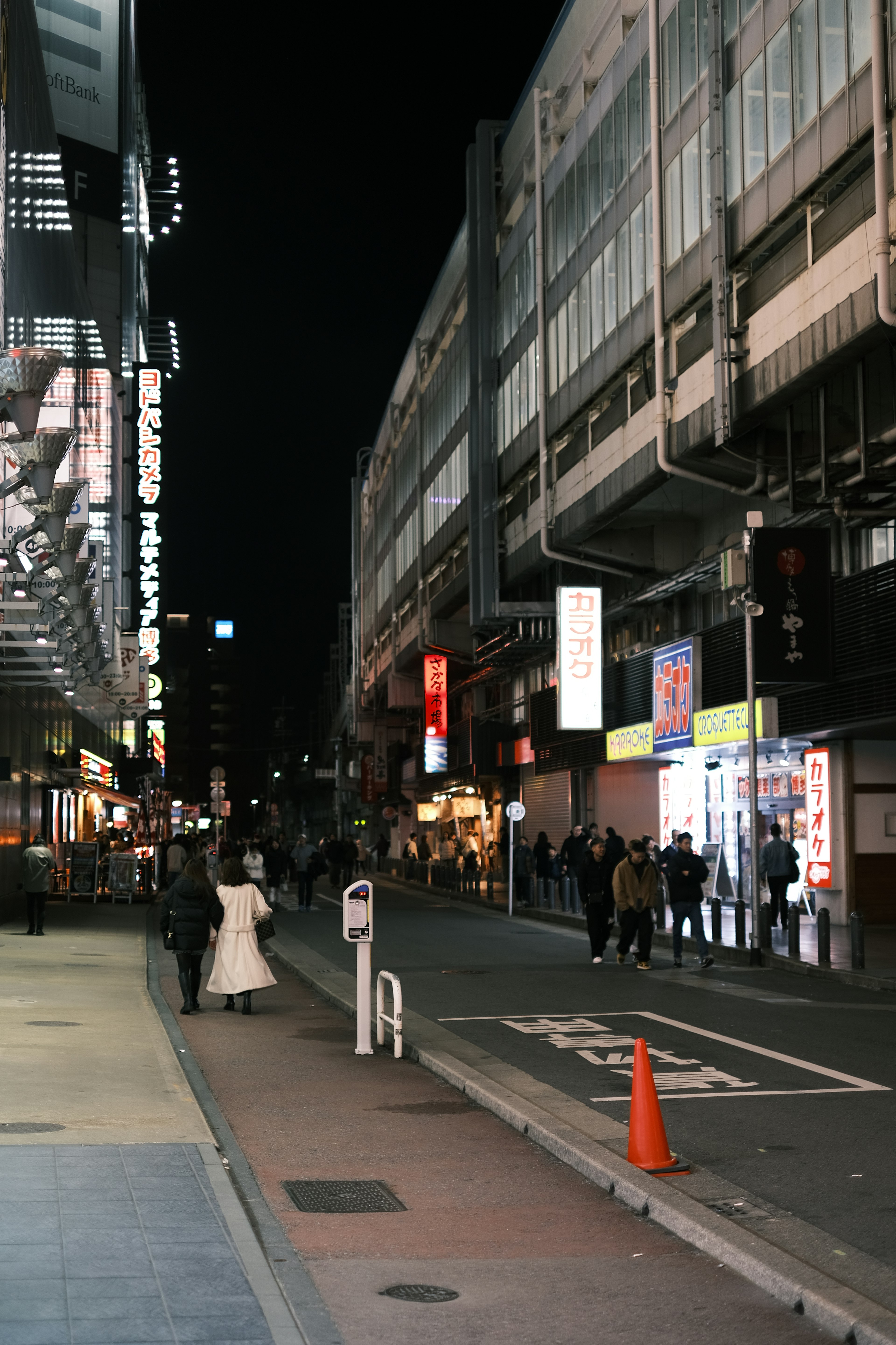 Paesaggio urbano notturno con una donna in abito bianco e persone che camminano