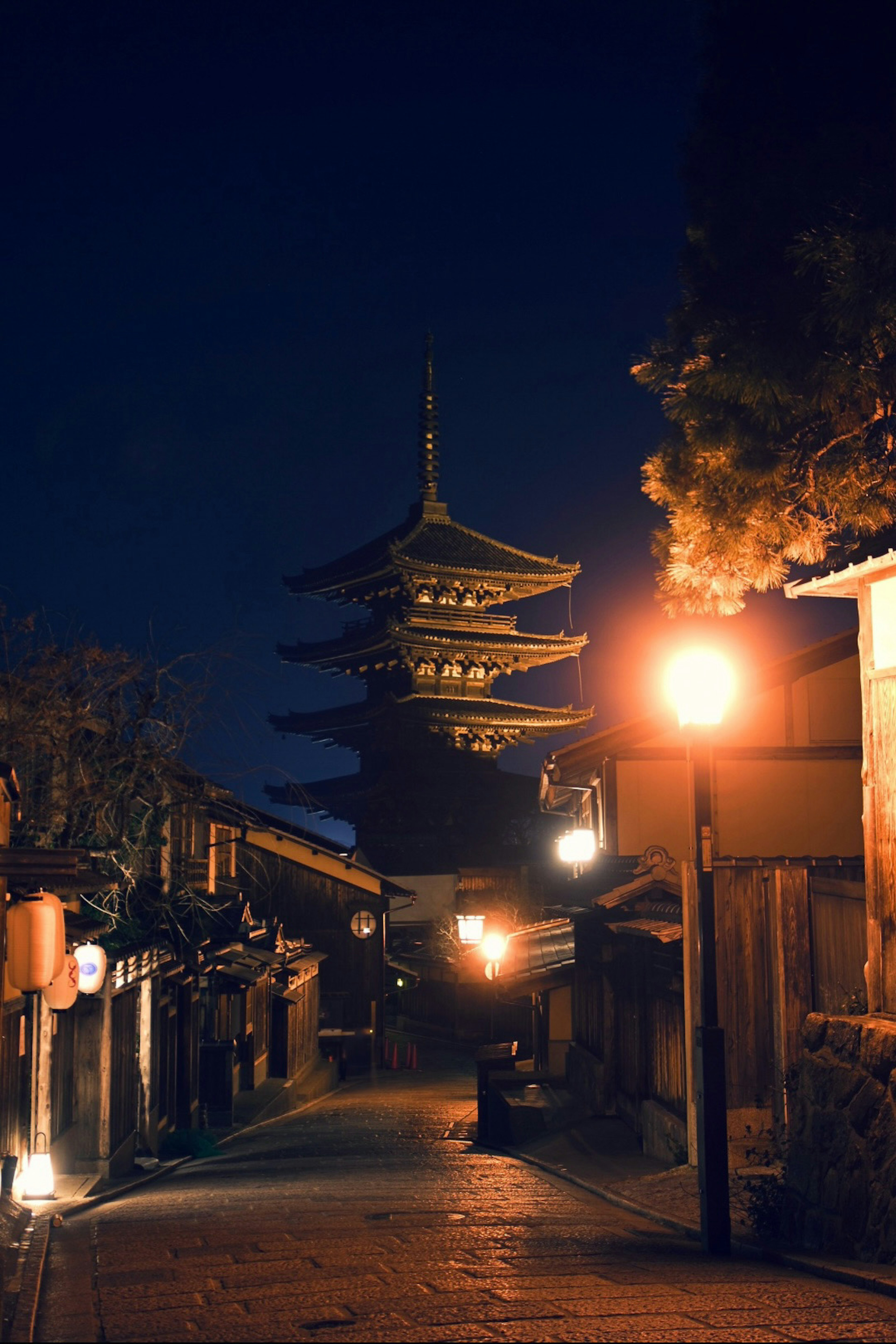 夜の京都の街並みにそびえる五重塔と街灯