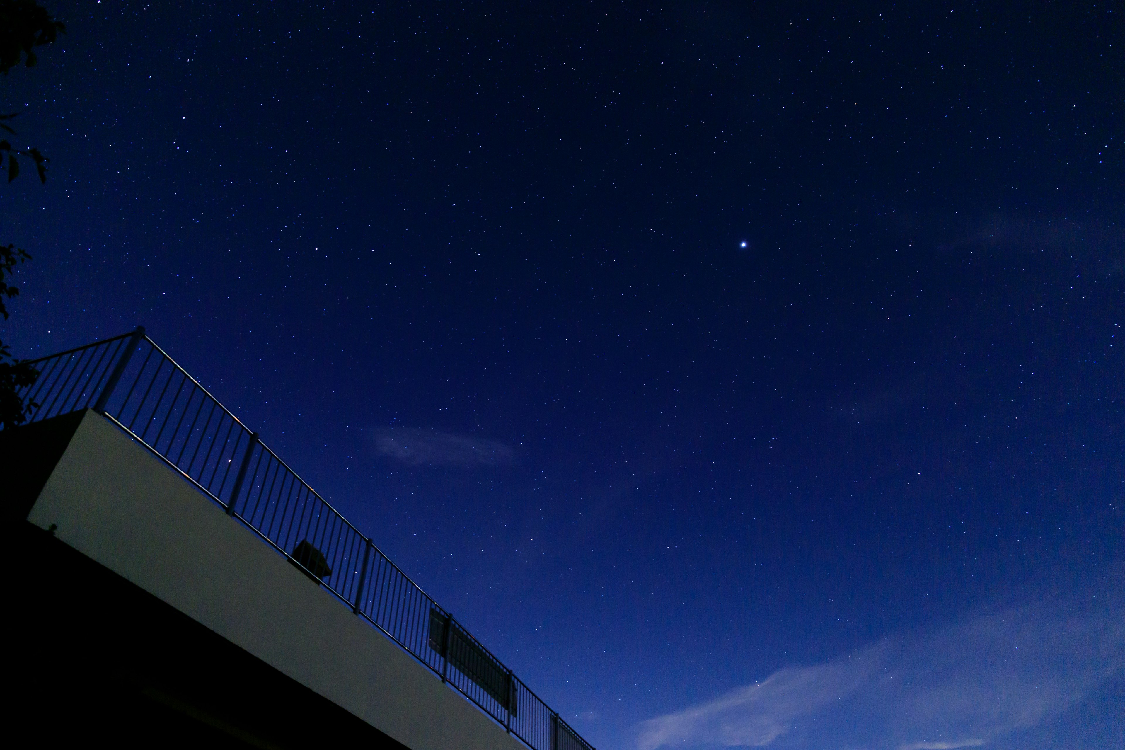 Cielo nocturno lleno de estrellas y la silueta de un balcón