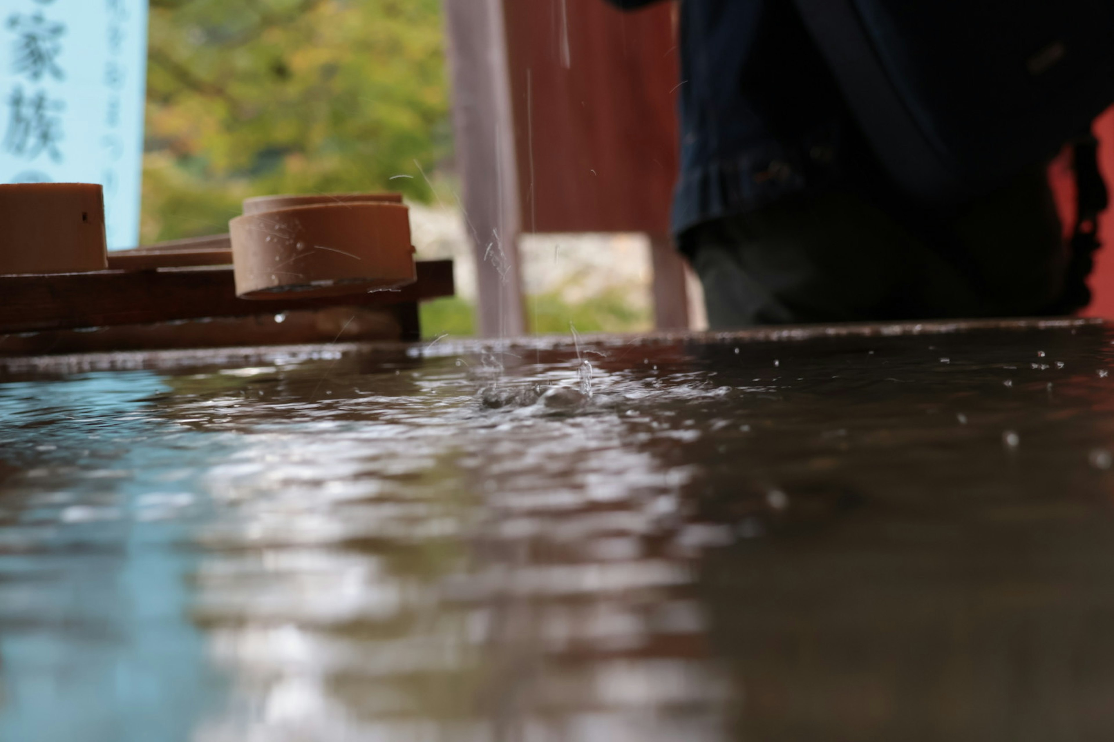 Wellen breiten sich auf der Wasseroberfläche aus mit einer unscharfen Figur im Hintergrund