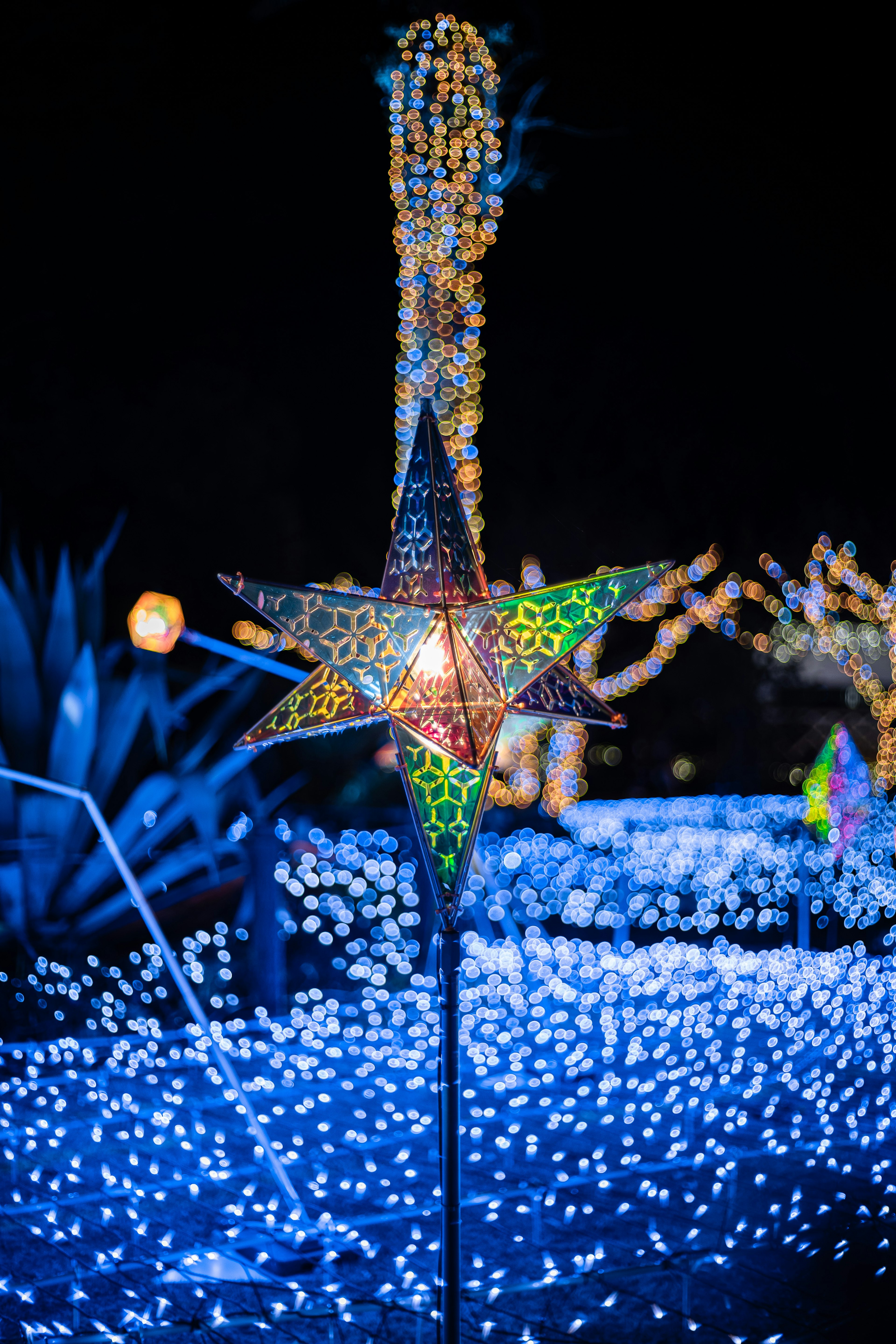 Bunte sternförmige Lampe leuchtet in der Nacht mit blauem Licht im Hintergrund