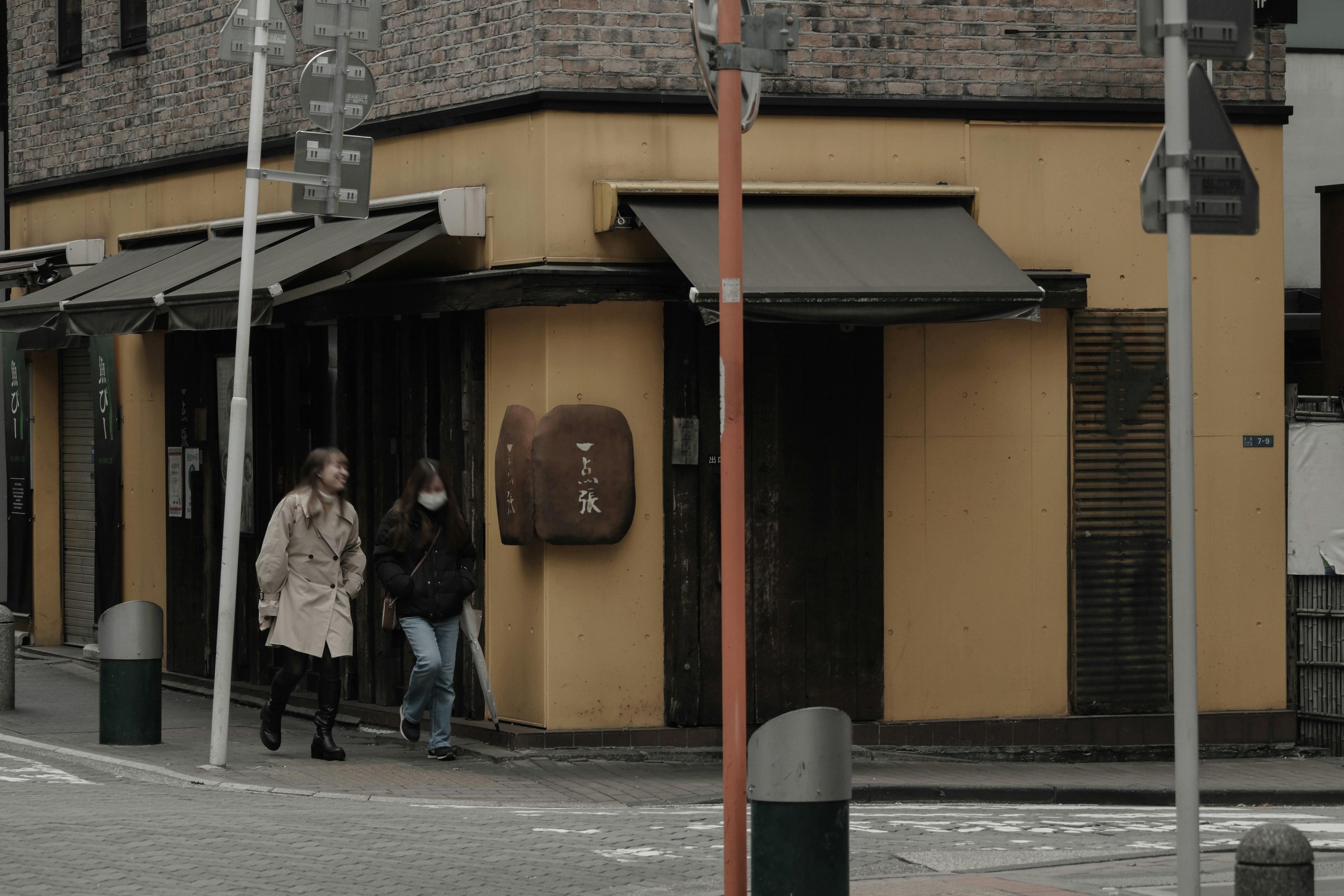 Angolo di strada con un edificio giallo e due pedoni