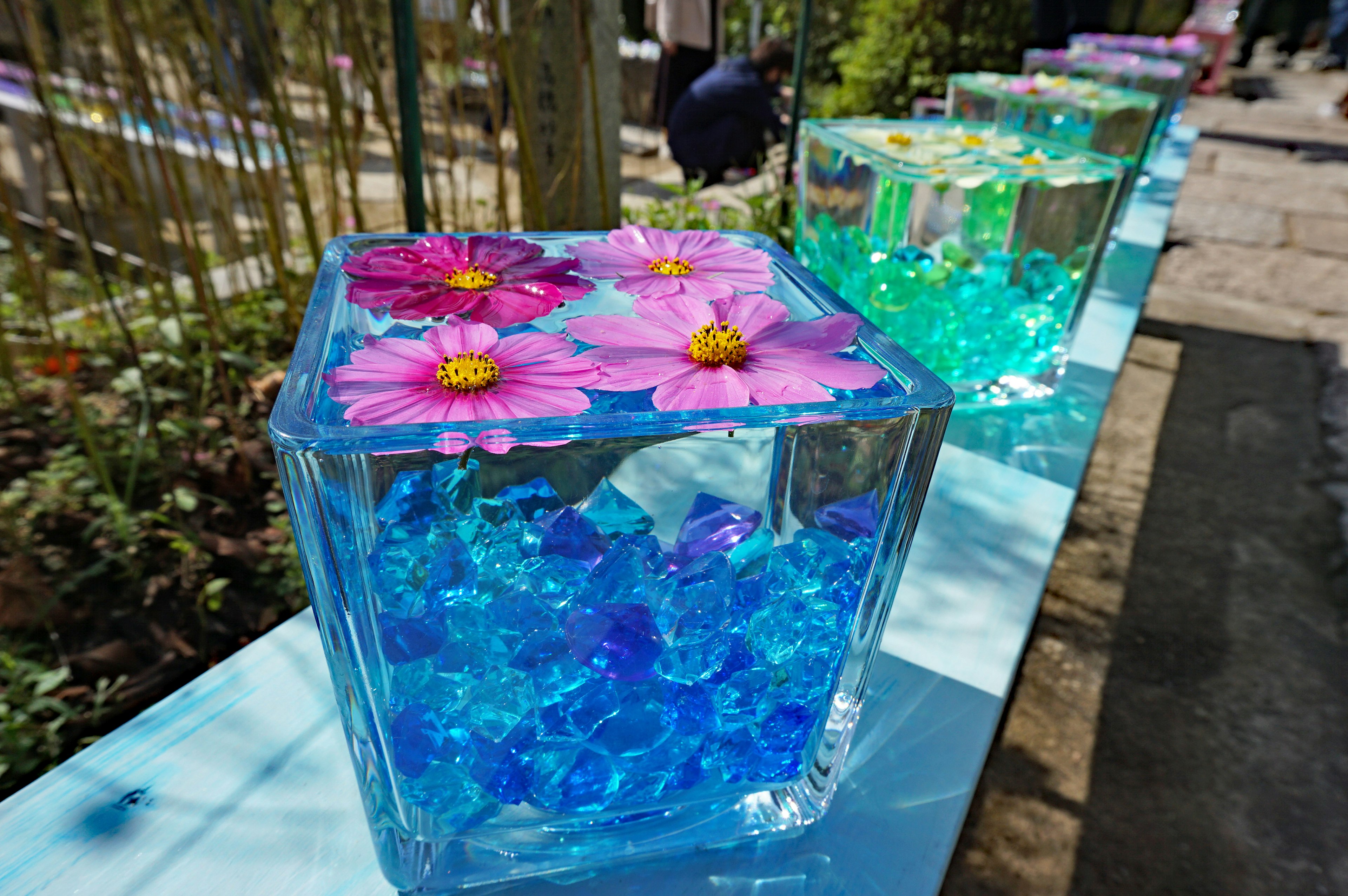 Art piece featuring transparent blocks filled with colorful flowers and gems