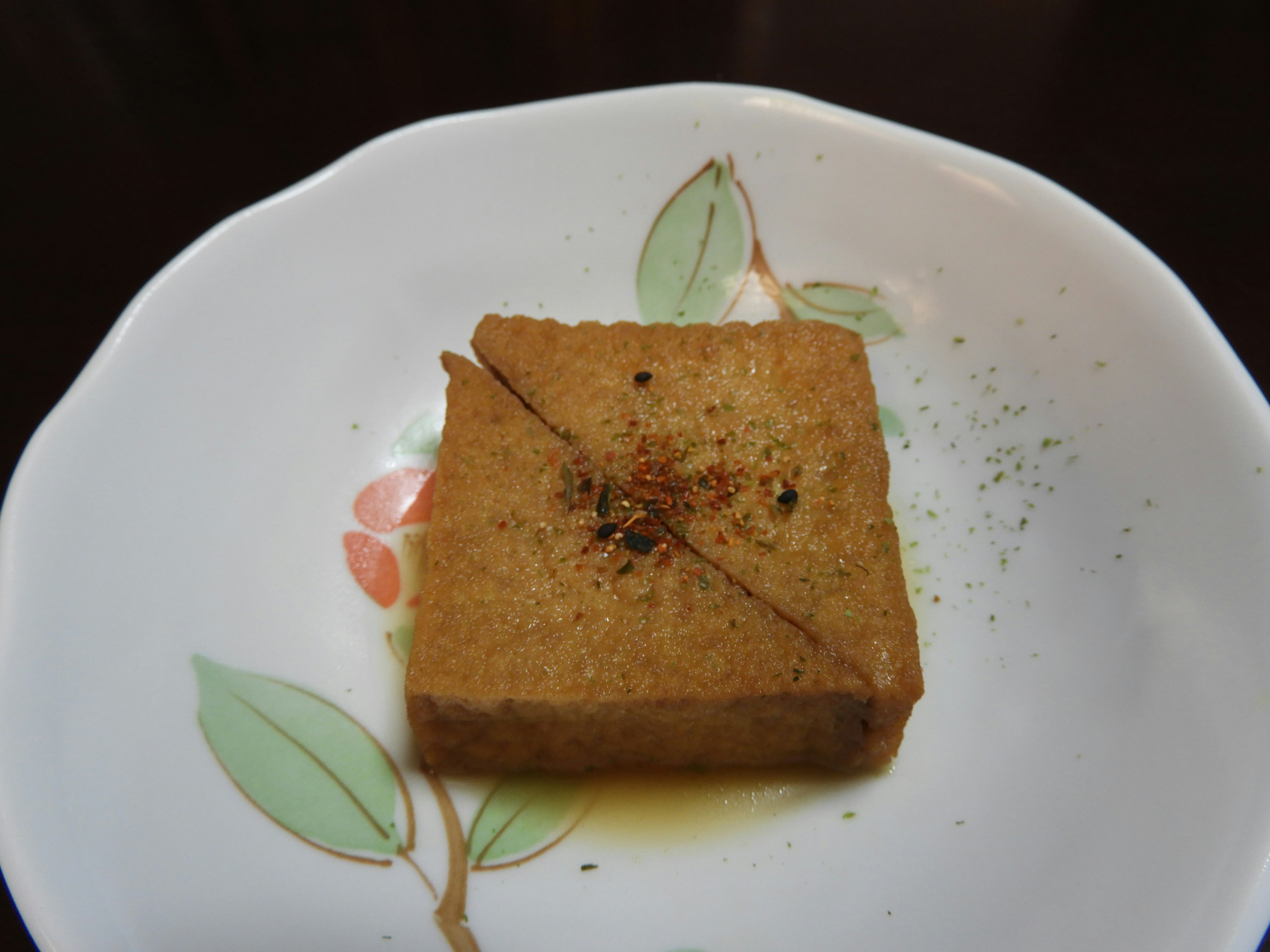 A square piece of tofu served on a white plate