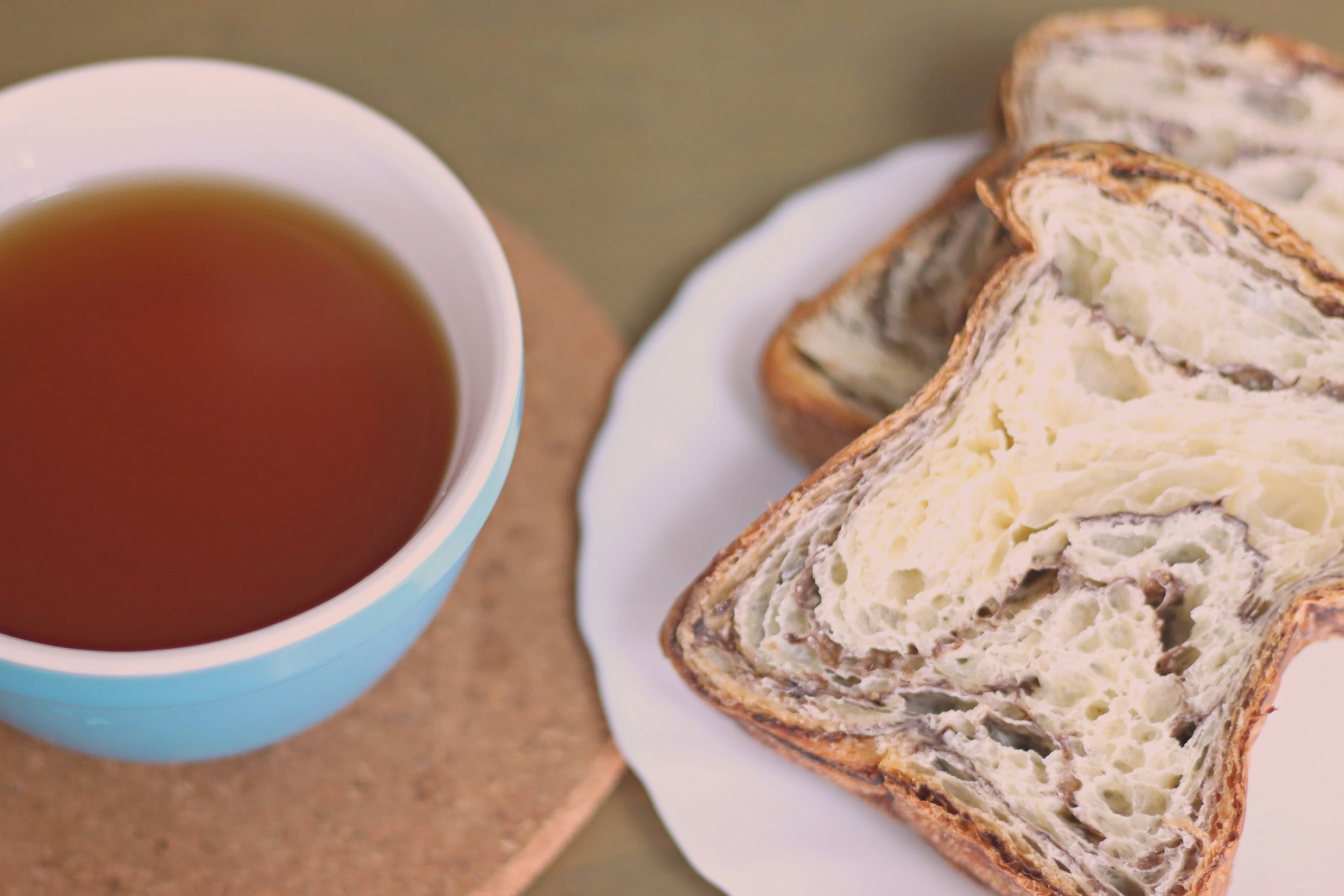 A cup of tea next to slices of marble bread on a plate