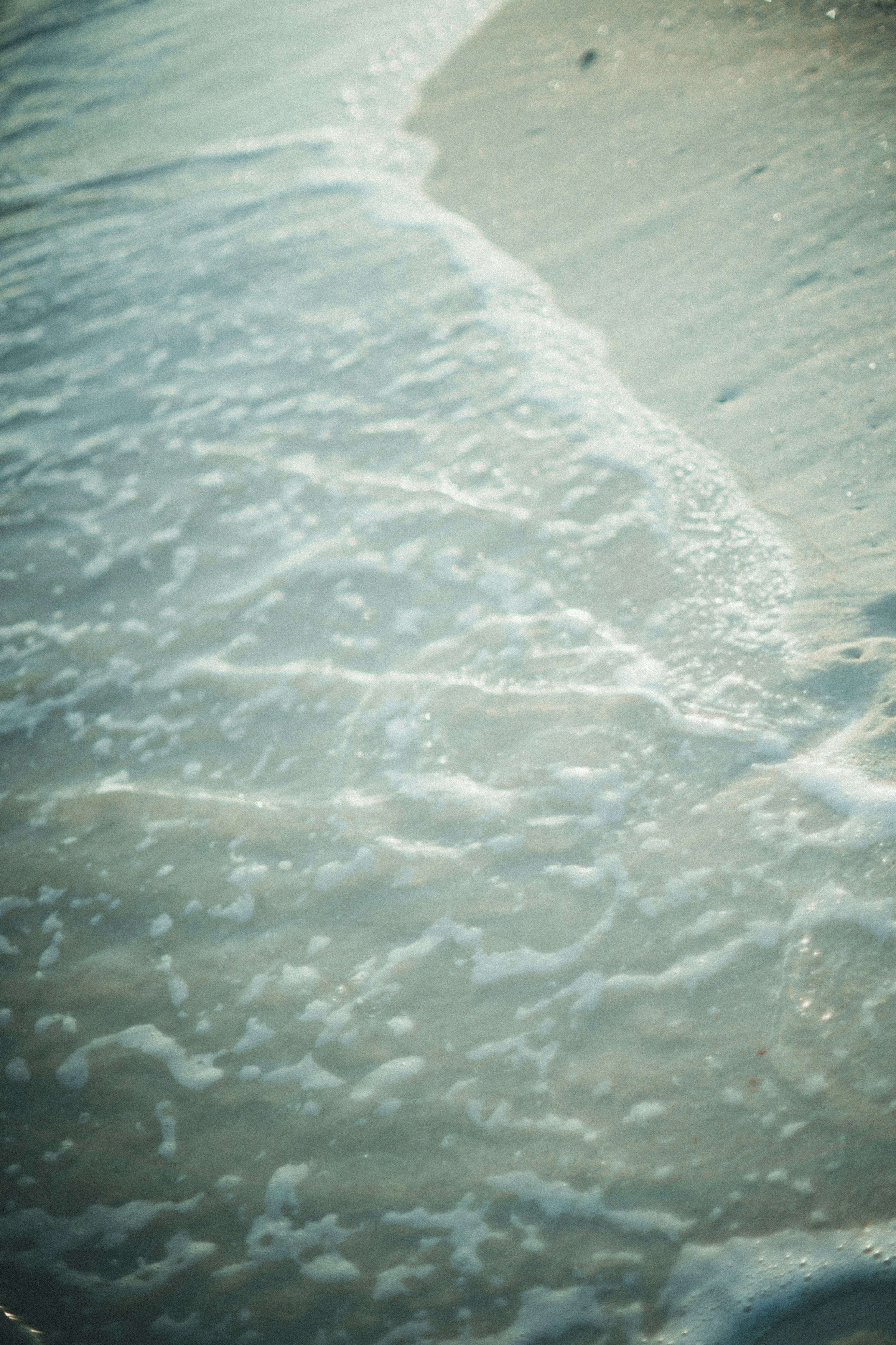 Wellen, die sanft an einen Sandstrand schlagen