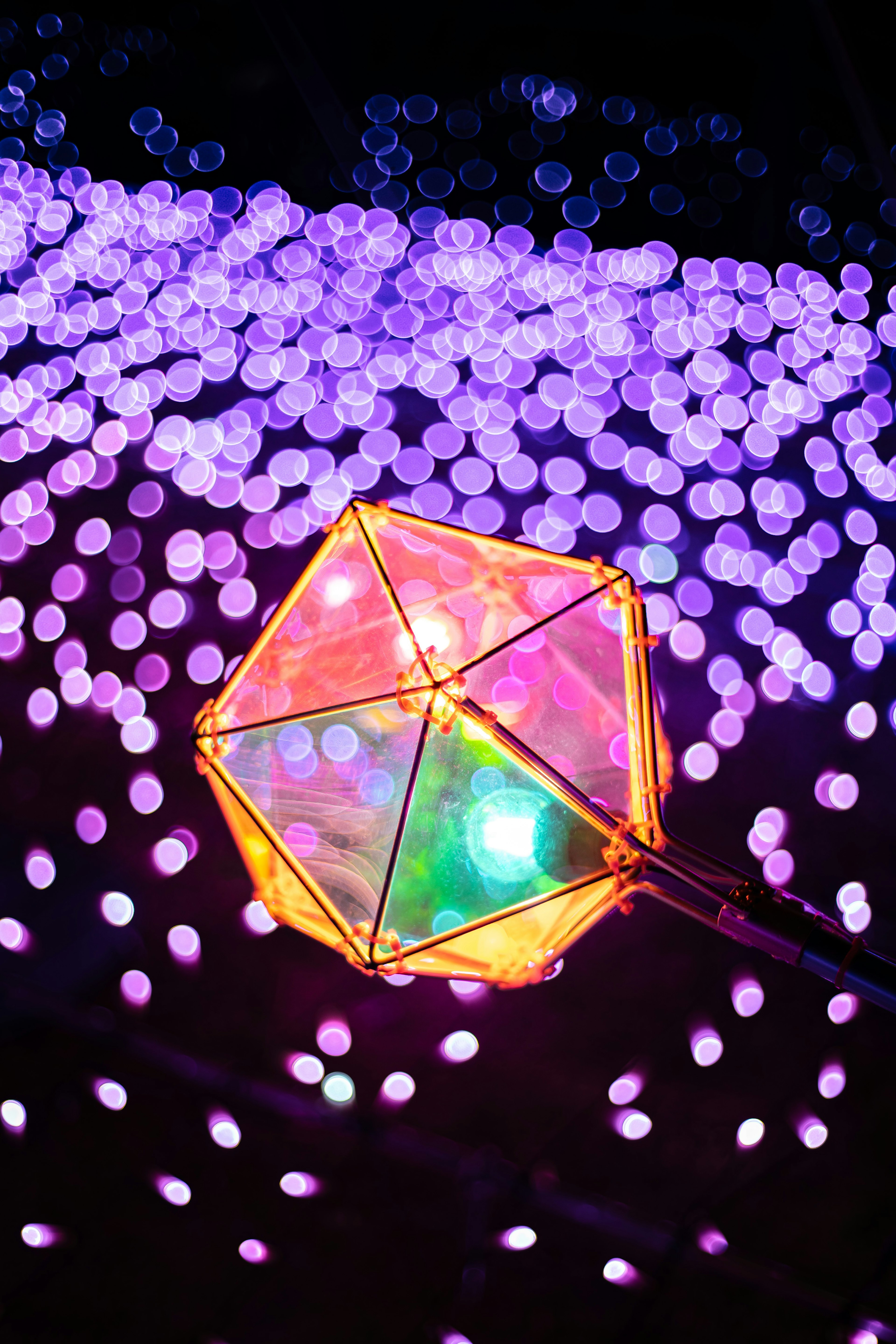 A colorful polyhedral object with lights set against a blurred purple background