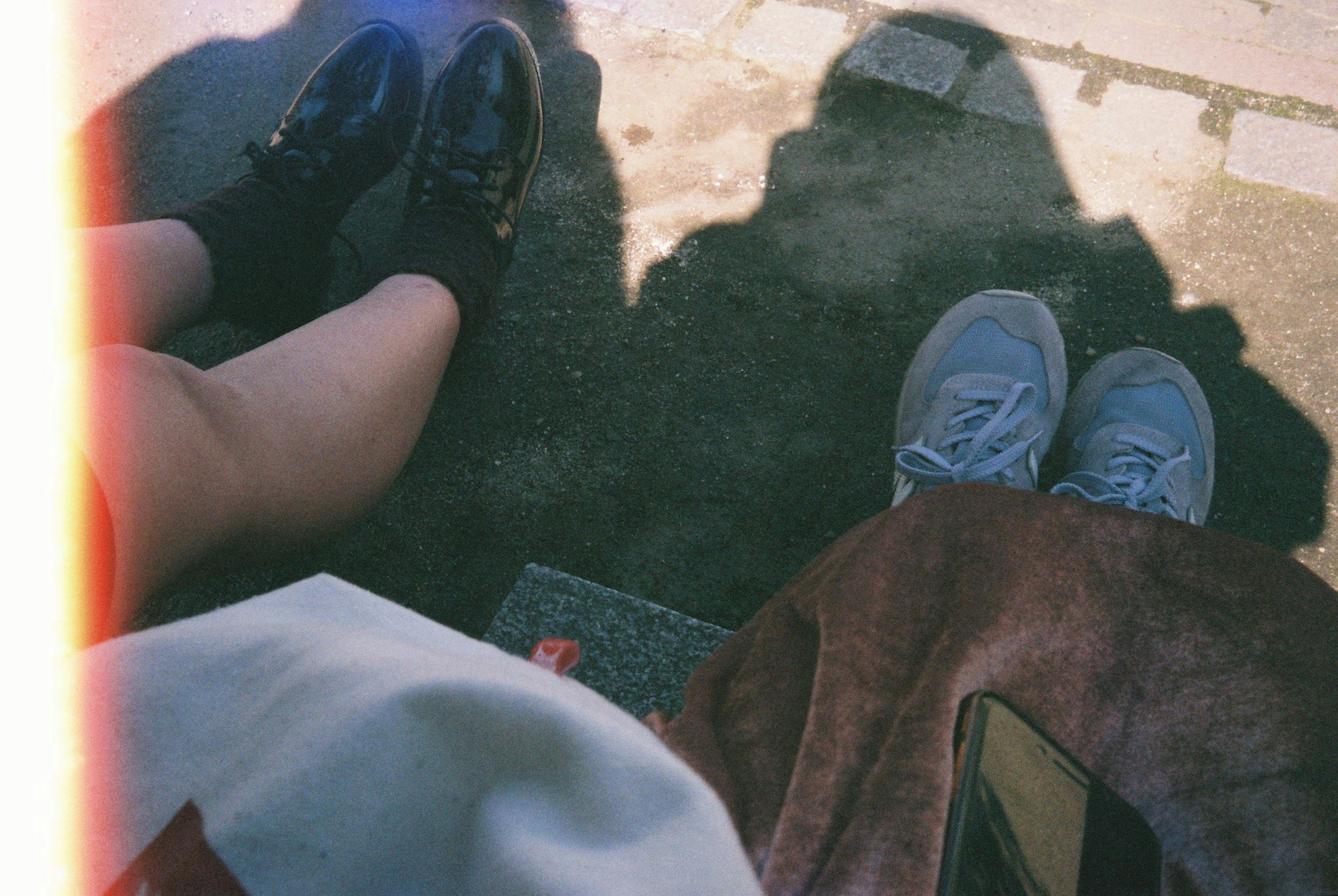 Photo showing two pairs of feet one in black shoes and the other in blue sneakers