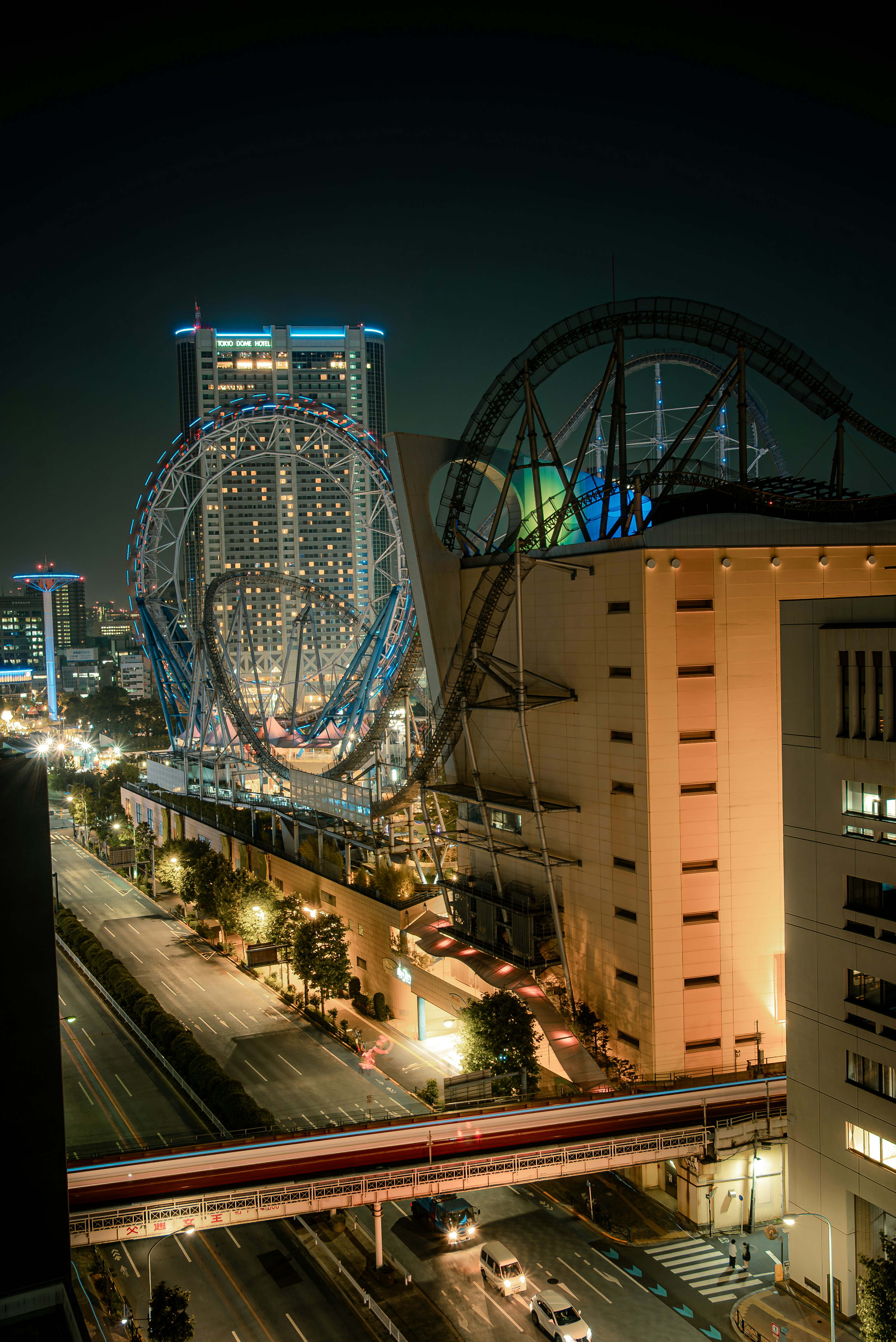 夜景の都市風景にある遊園地のジェットコースターと高層ビル