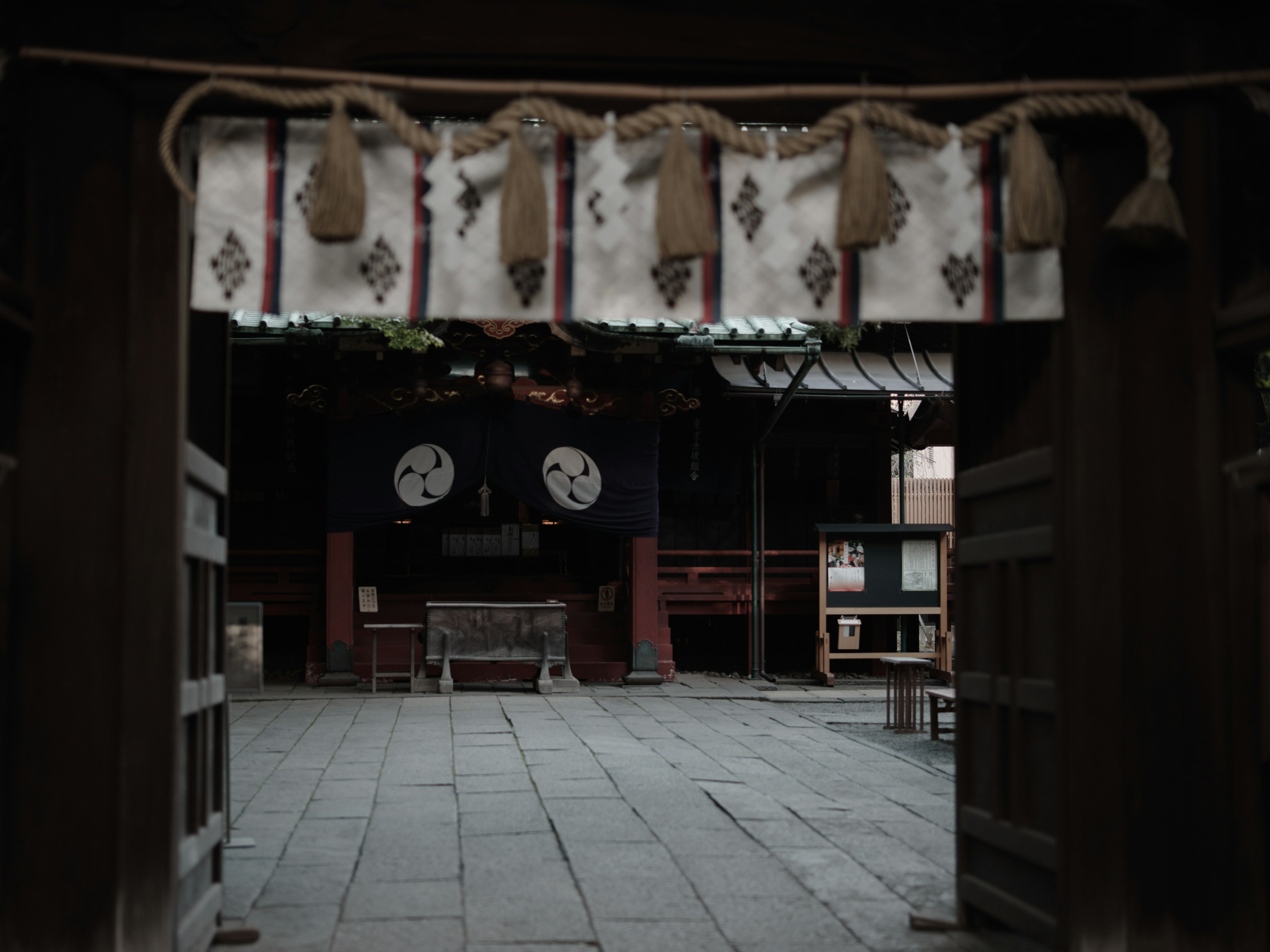 門を通して見える静かな神社の内部と古い時計