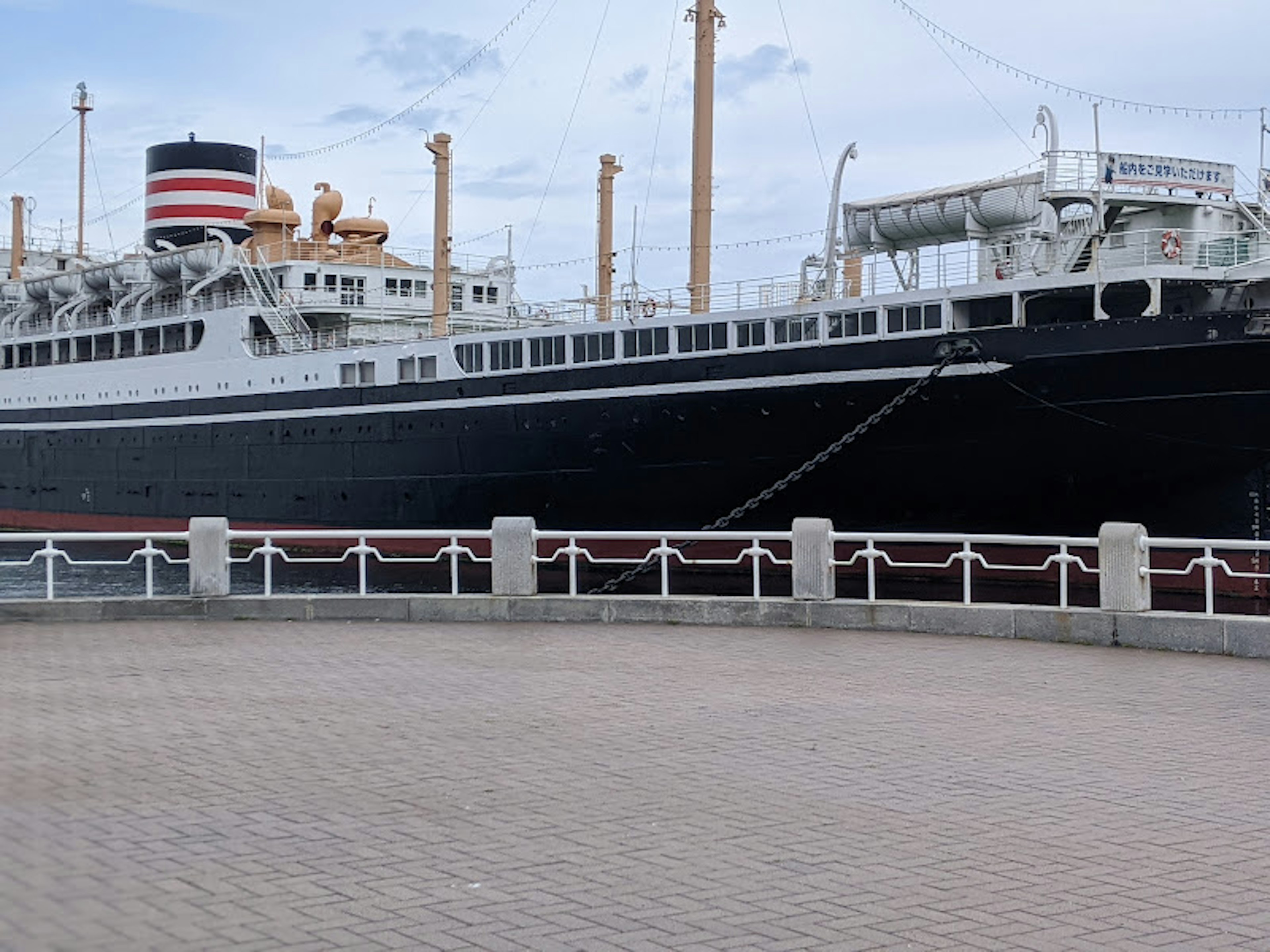 Large passenger ship with a black hull docked at the pier