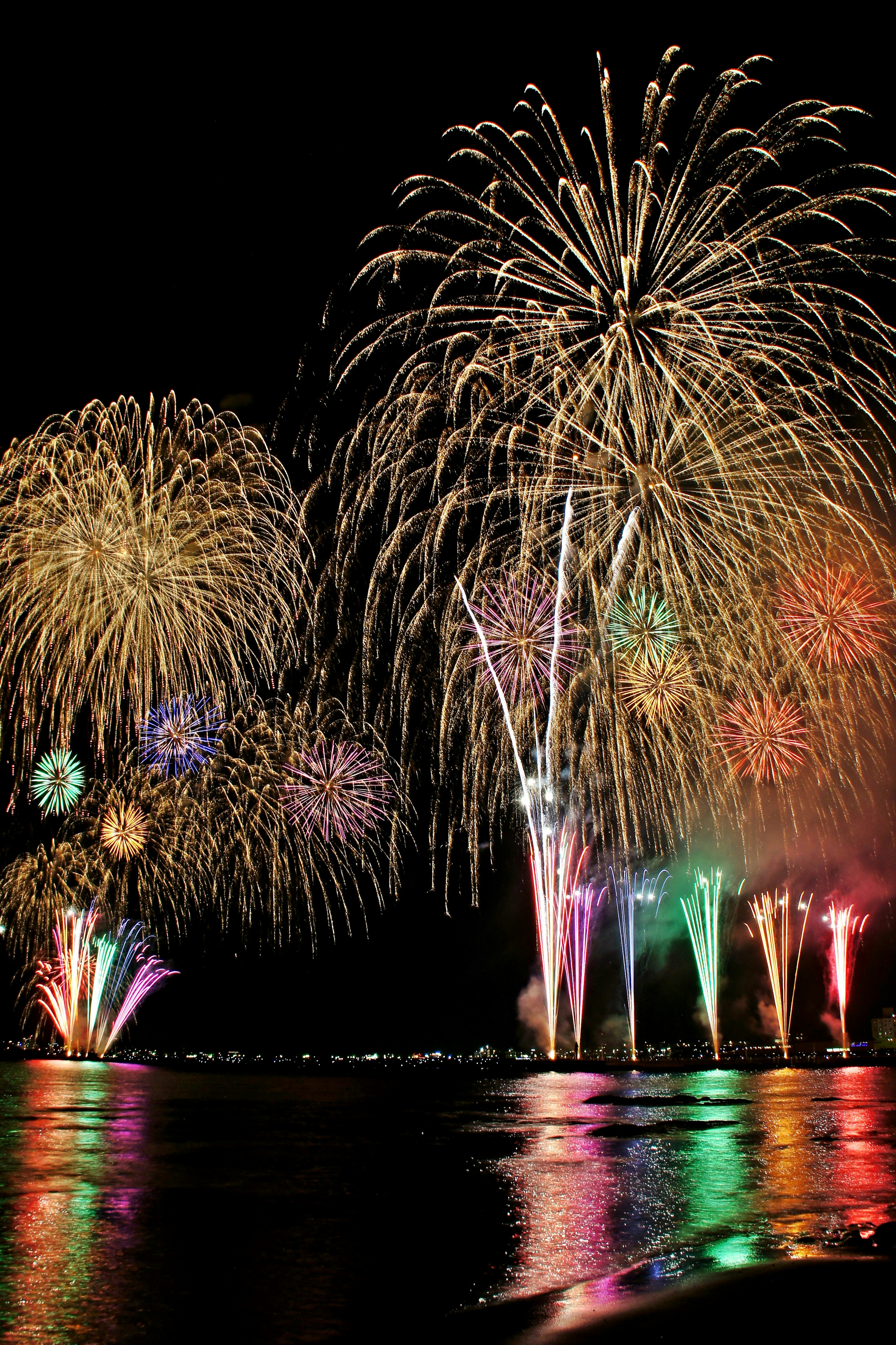 Ein wunderschönes Feuerwerk im Nachthimmel Bunte Lichter spiegeln sich auf der Wasseroberfläche