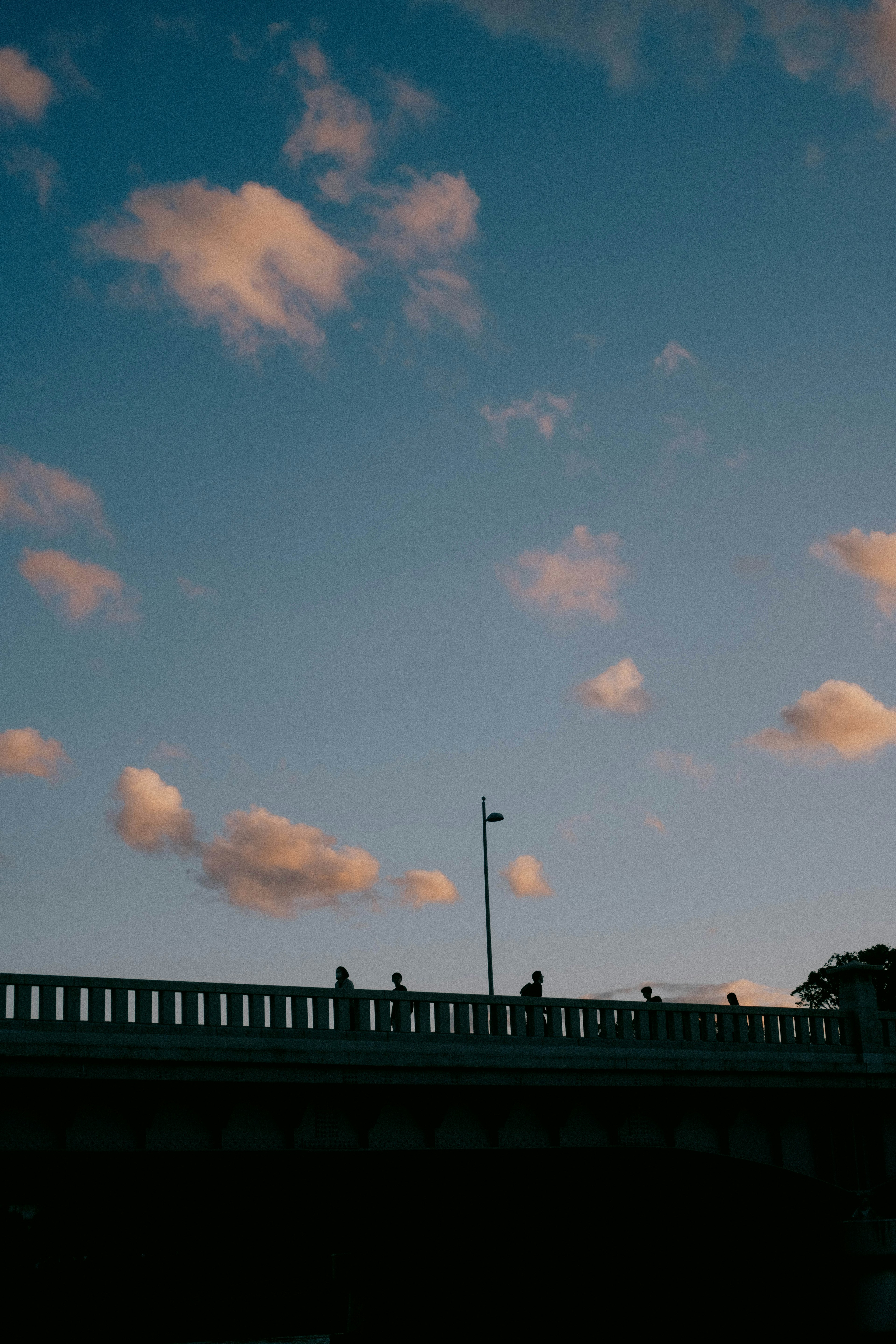 Siluet jembatan melawan langit biru dengan awan