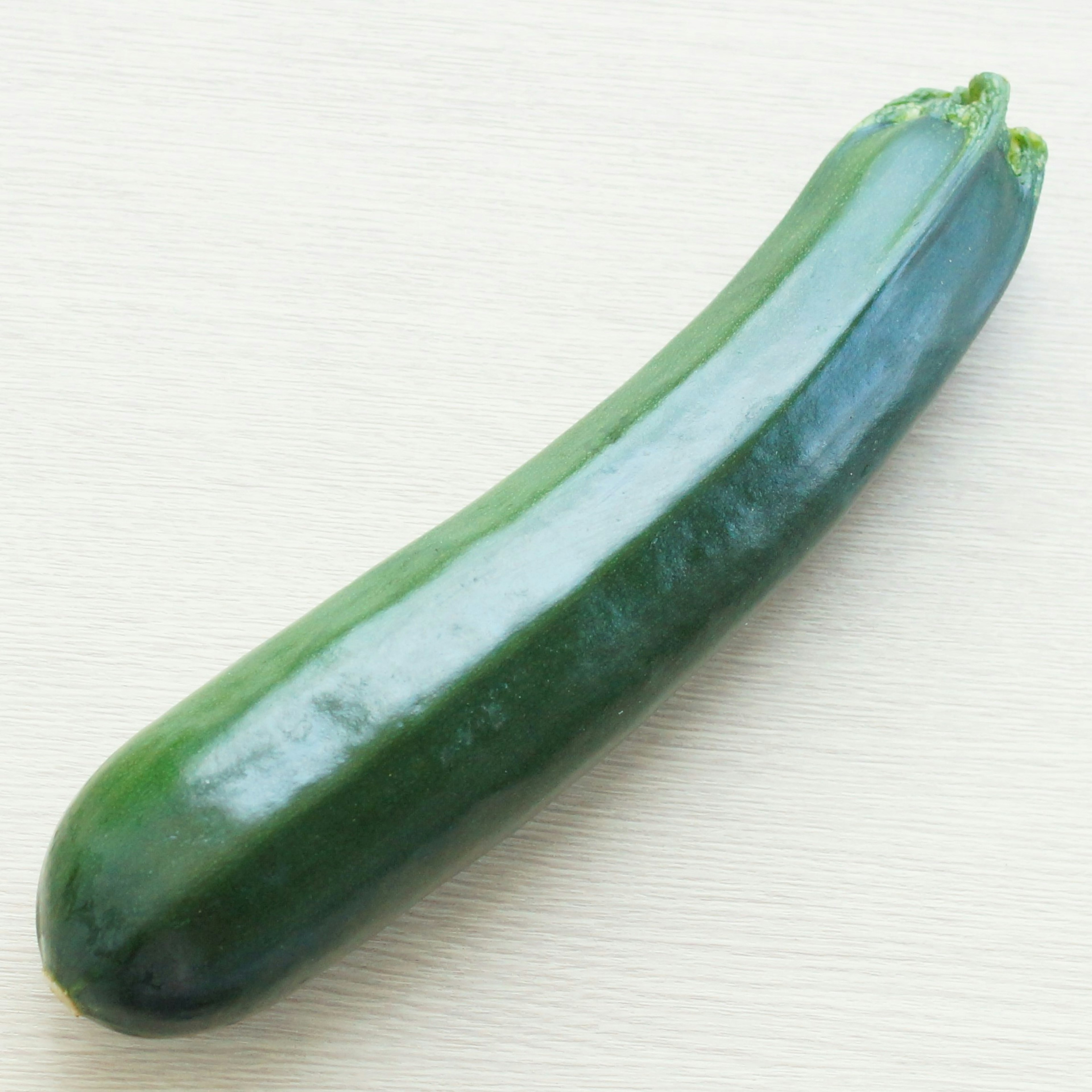 Une courgette verte posée sur une surface plane