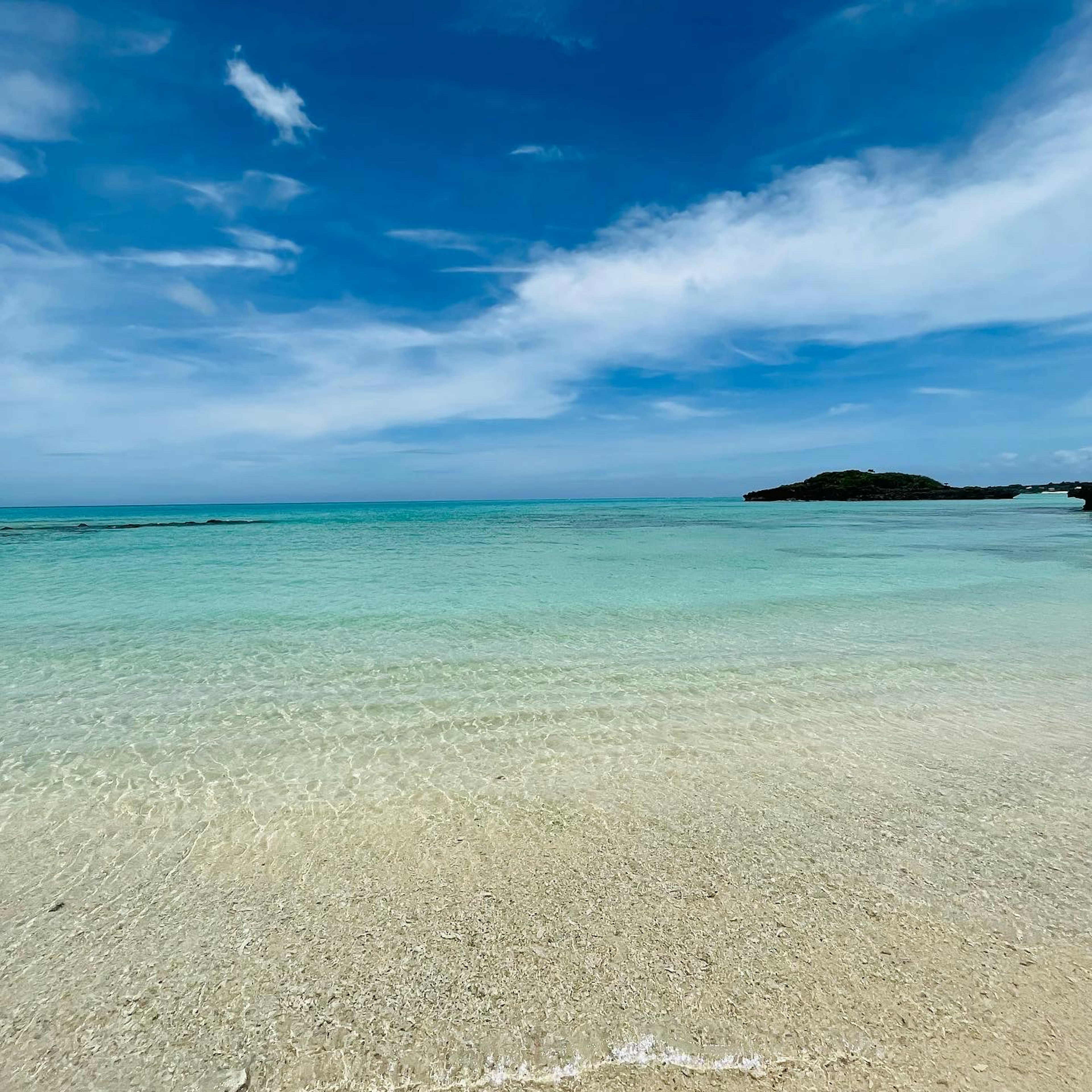 Escena de playa con agua turquesa clara y cielo azul