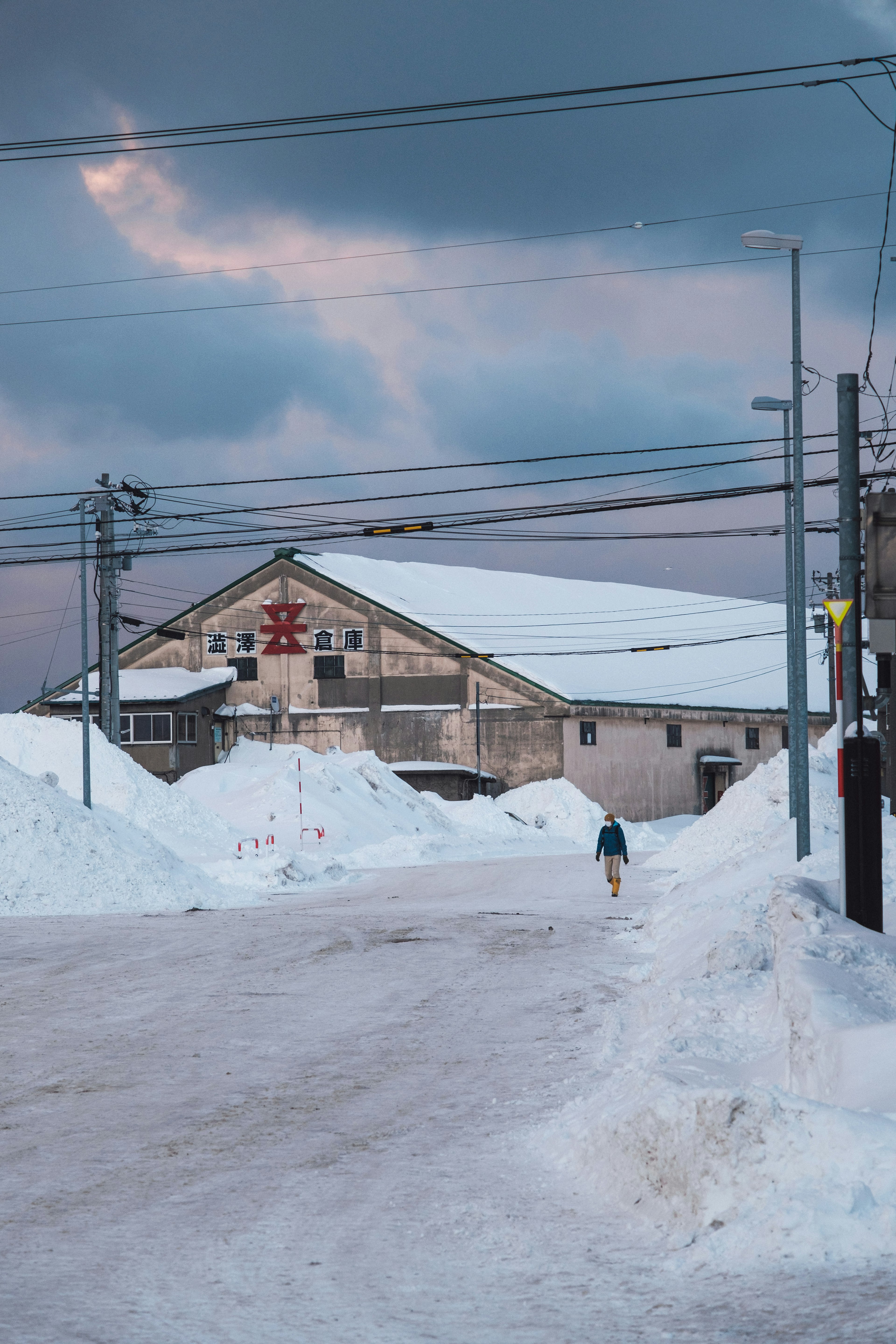 Una persona che cammina su una strada innevata con un edificio sullo sfondo