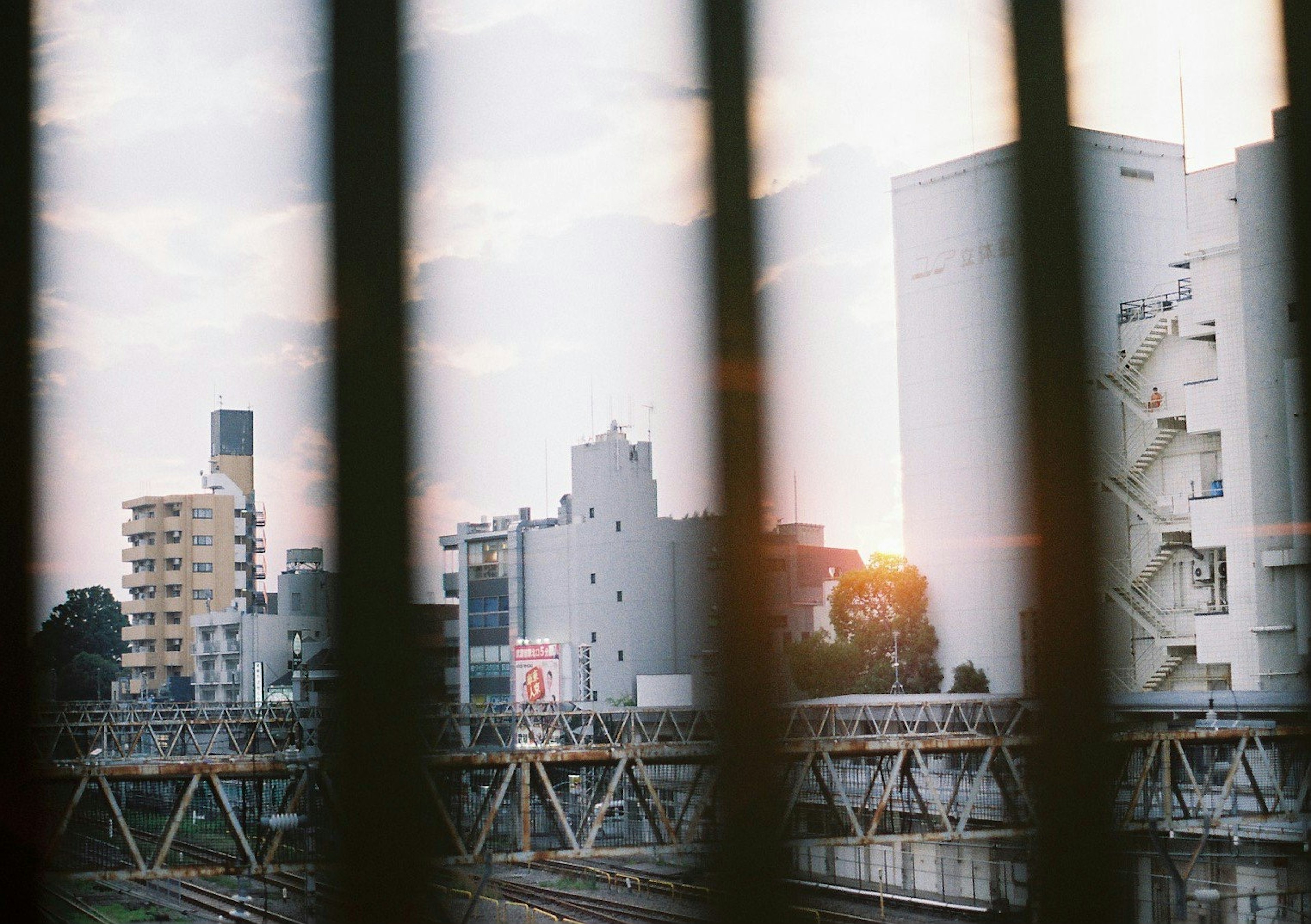 夕日を背景にした都市の景色が見える鉄道の窓越し