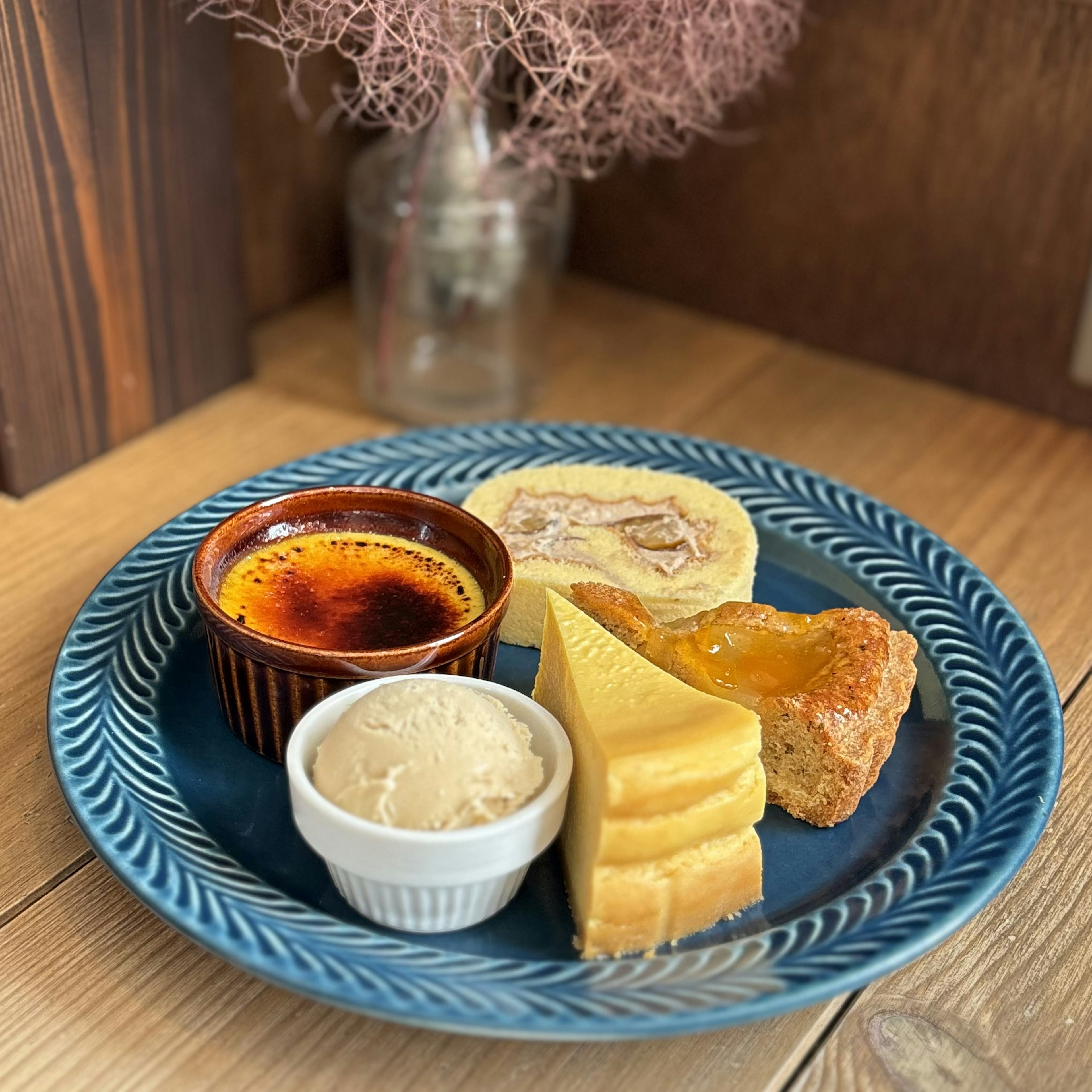 Dessert platter on a blue plate featuring crème brûlée vanilla ice cream fruit tart and cookies