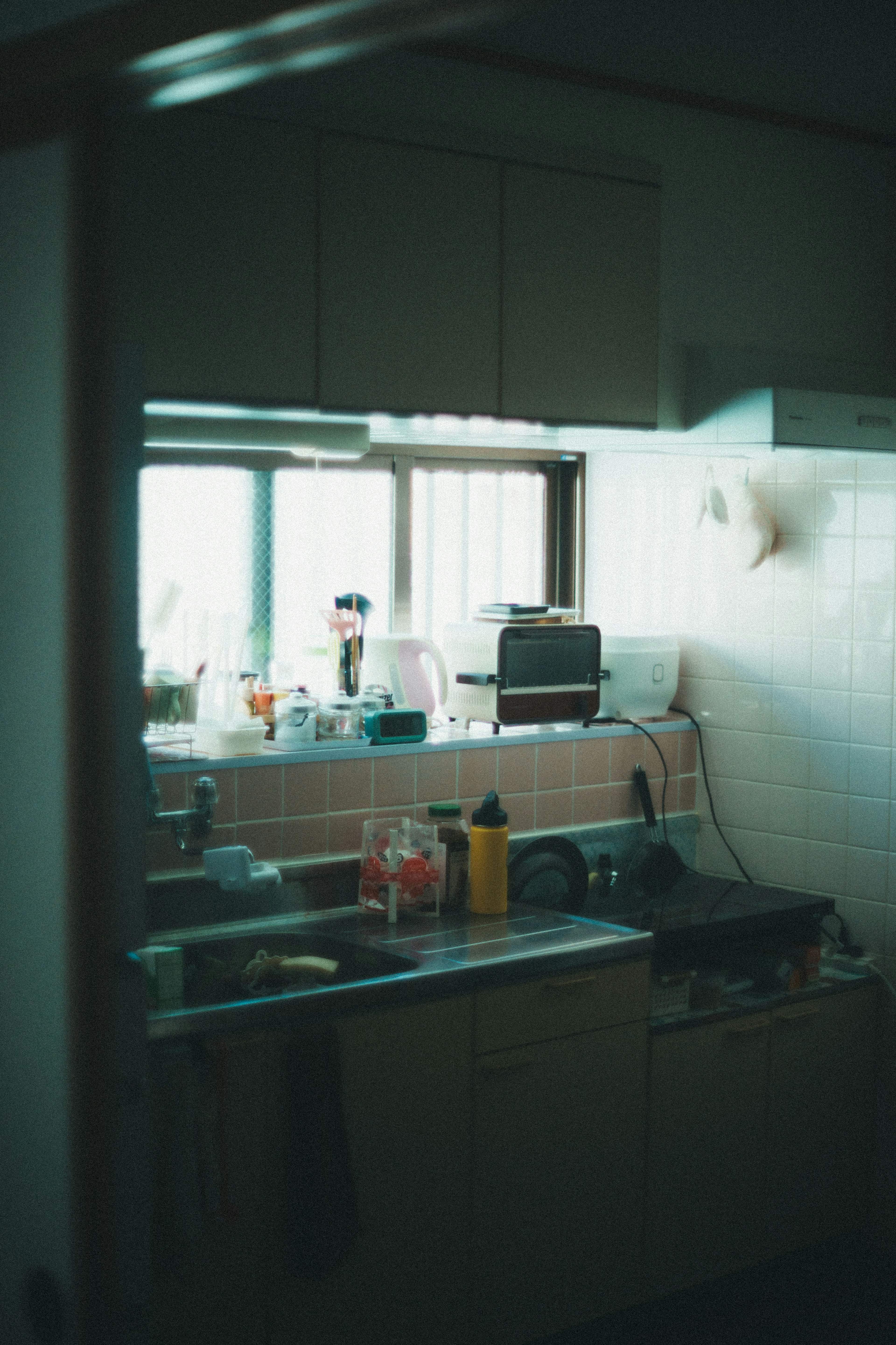 Bright kitchen scene with a window, dishes in the sink, and cooking utensils on the counter