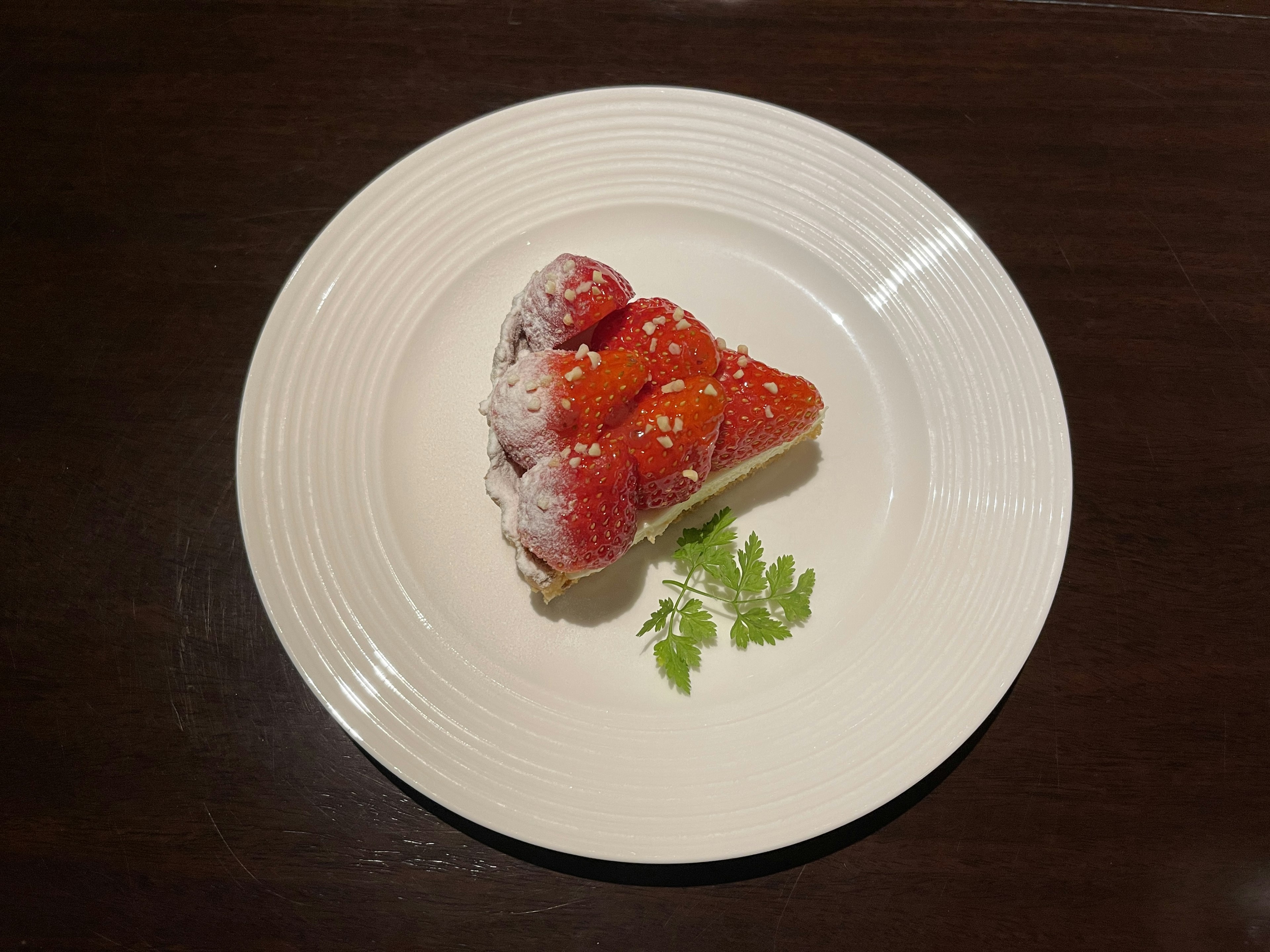 Un hermoso postre rojo adornado con hojas verdes en un plato blanco