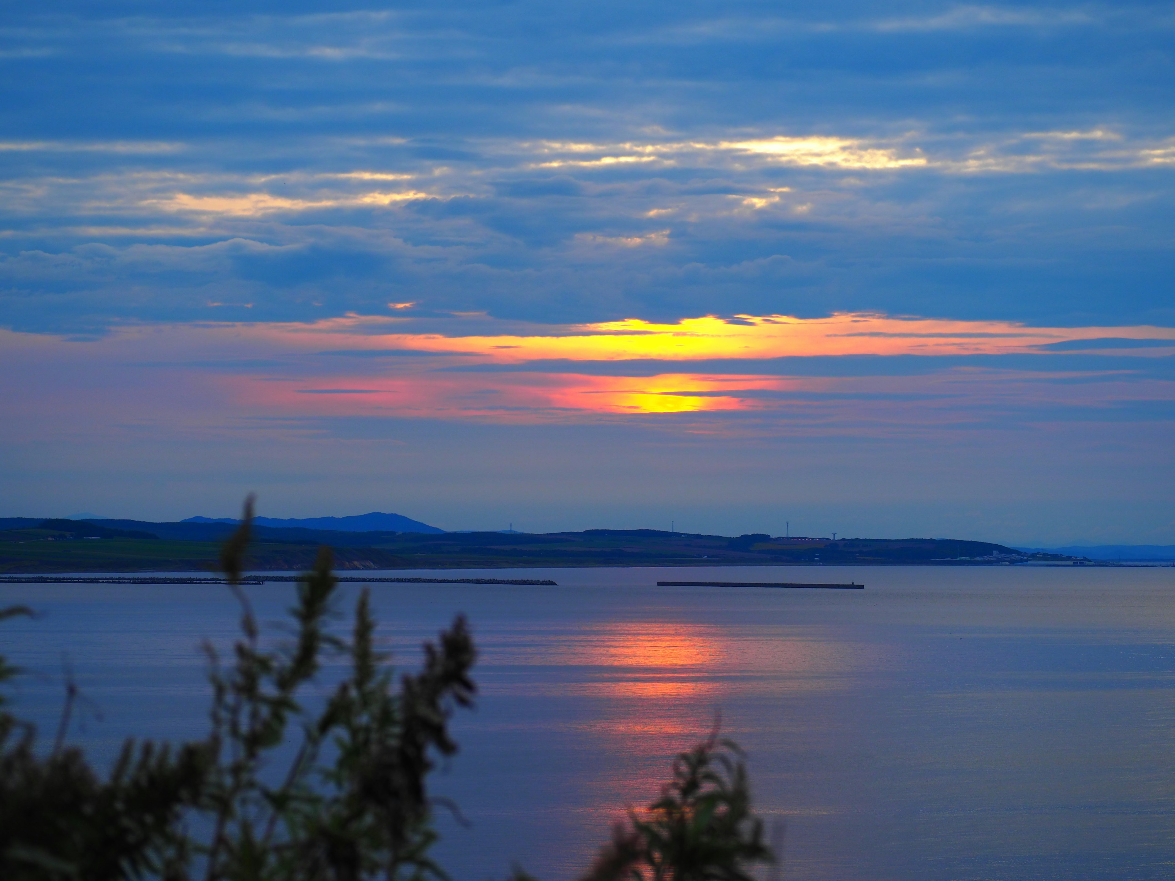 Une vue sereine sur un lac avec un ciel bleu et un coucher de soleil orange