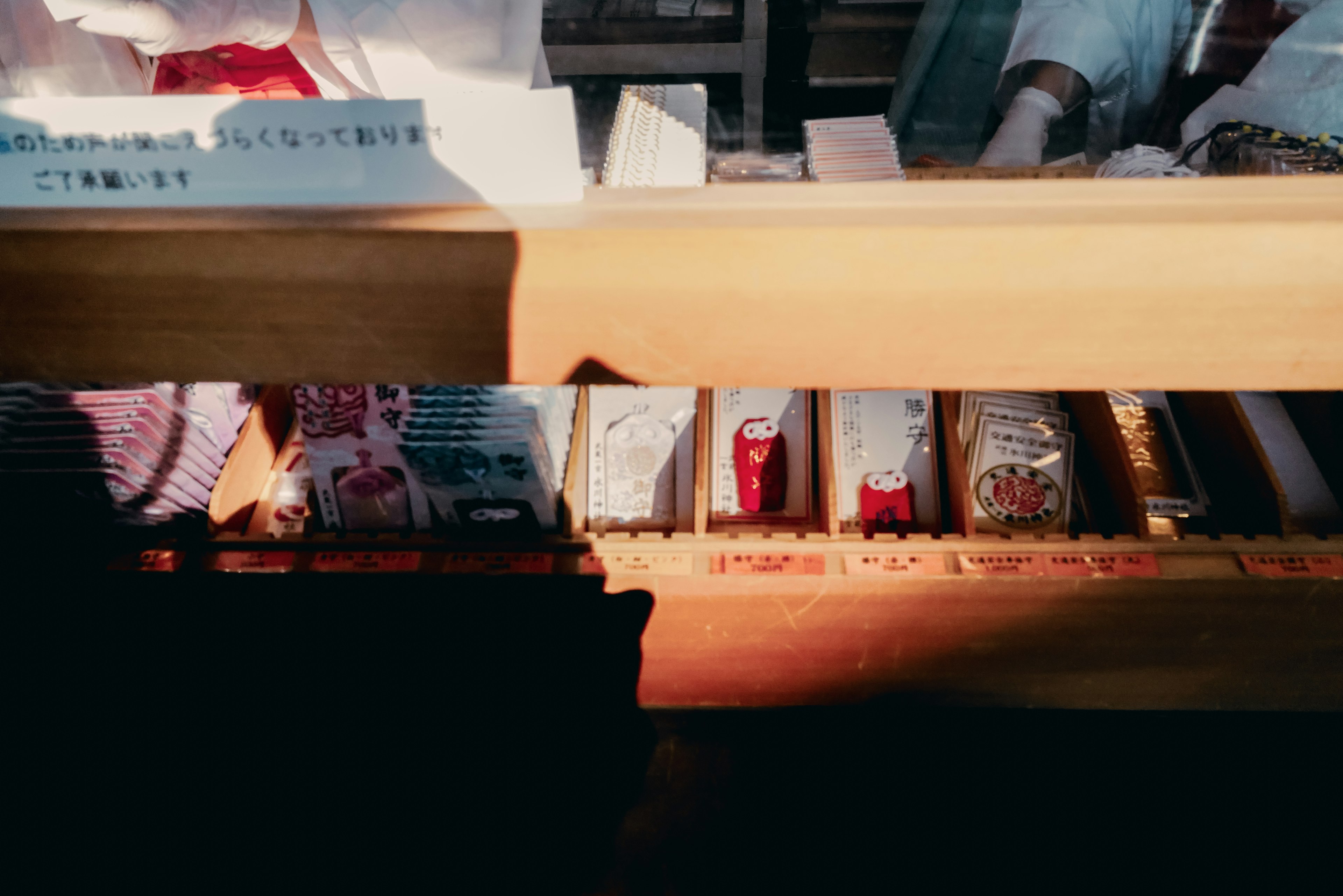 Colorful packaged items arranged on a wooden shelf with staff in the background